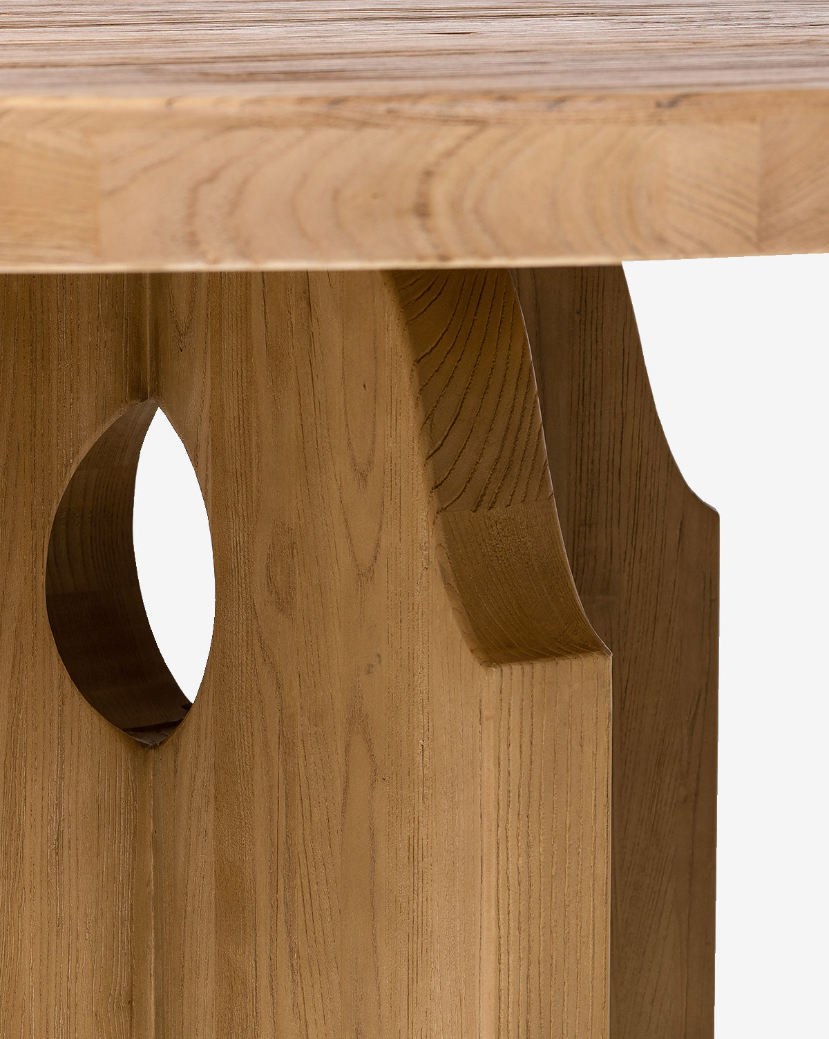 Close-up of the Bayard Round Dining Table’s edge and leg, crafted from reclaimed elm wood with a decorative cutout and carved details in a light natural finish, echoing Swedish-inspired design, by McGee & Co.