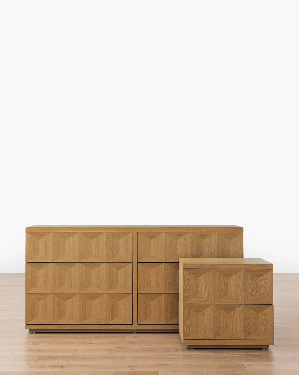 The Beacon Nightstand features geometric, textured drawer fronts in white oak for modern bedroom storage, displayed on a light wood floor with a plain white background, by McGee & Co.