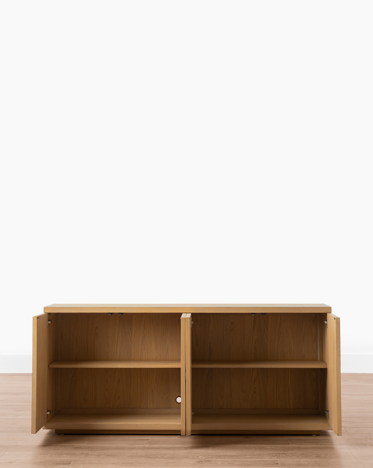 The Beacon Sideboard showcases a neutral finish and two open doors with spacious storage, including two shelves, set on a wooden floor against a plain white wall by McGee & Co.