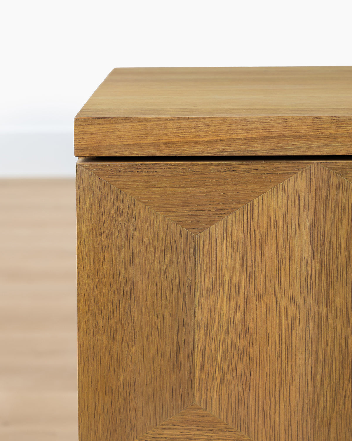 The Beacon Sideboard features a geometric diamond pattern on its doors and a neutral finish, providing ample storage, by McGee & Co. Shown here with a light wood floor and white wall backdrop.