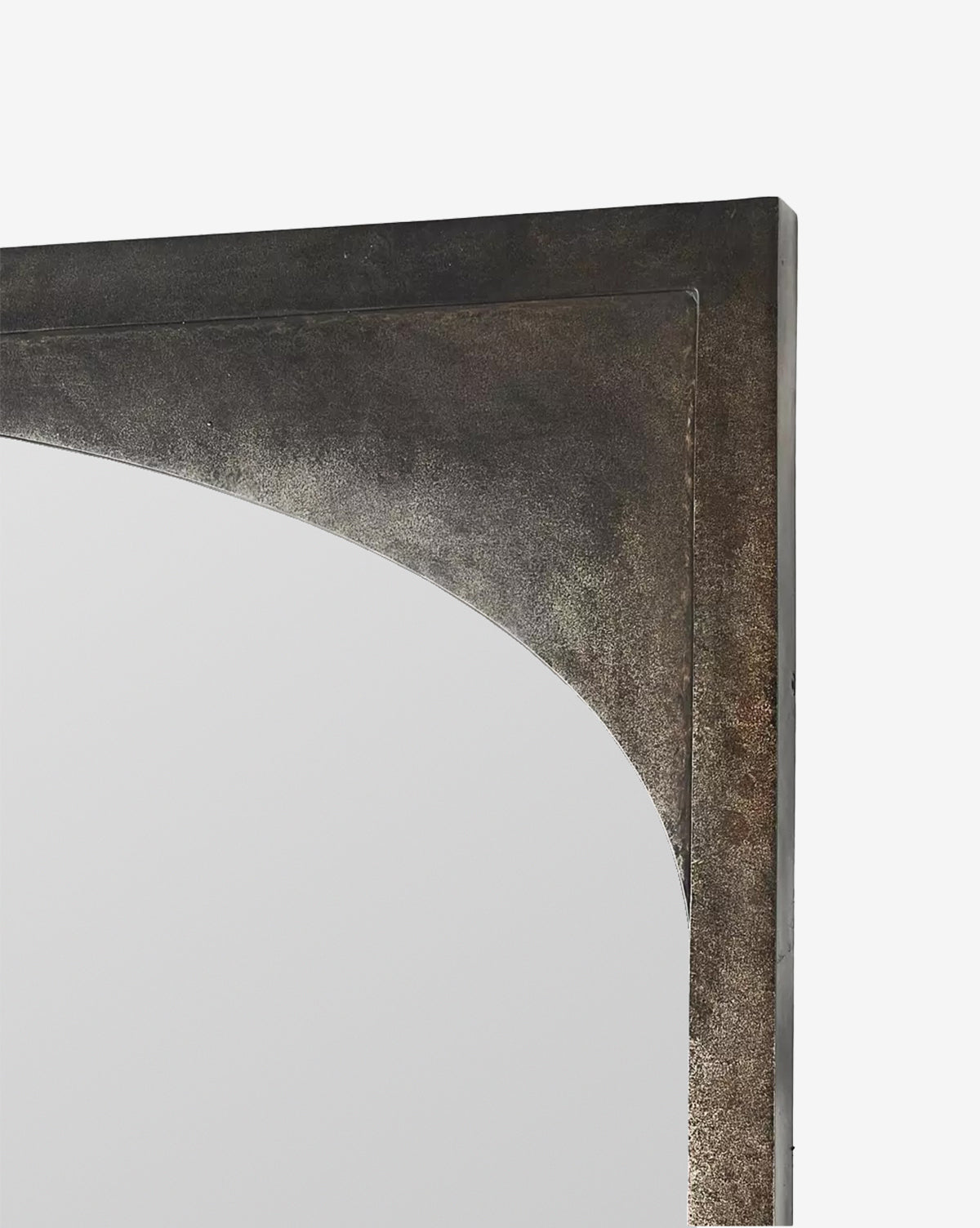Close-up of the top corner of the Beckington Floor Mirror, which has a thick iron frame in a burnished charcoal finish and a gracefully curved inner edge, set against a plain white background, by McGee & Co.