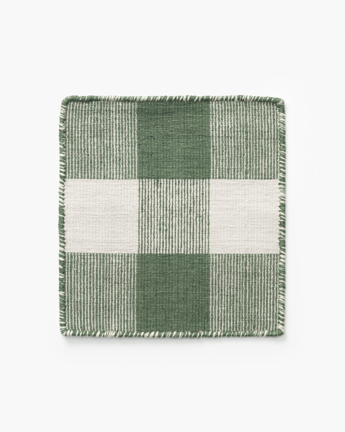 The Belleville Green Indoor/Outdoor Rug Swatch is a square fabric sample with a green and white checkered motif and fringed edges. Handwoven from recycled polyester, it features large alternating solid and striped squares by McGee & Co.