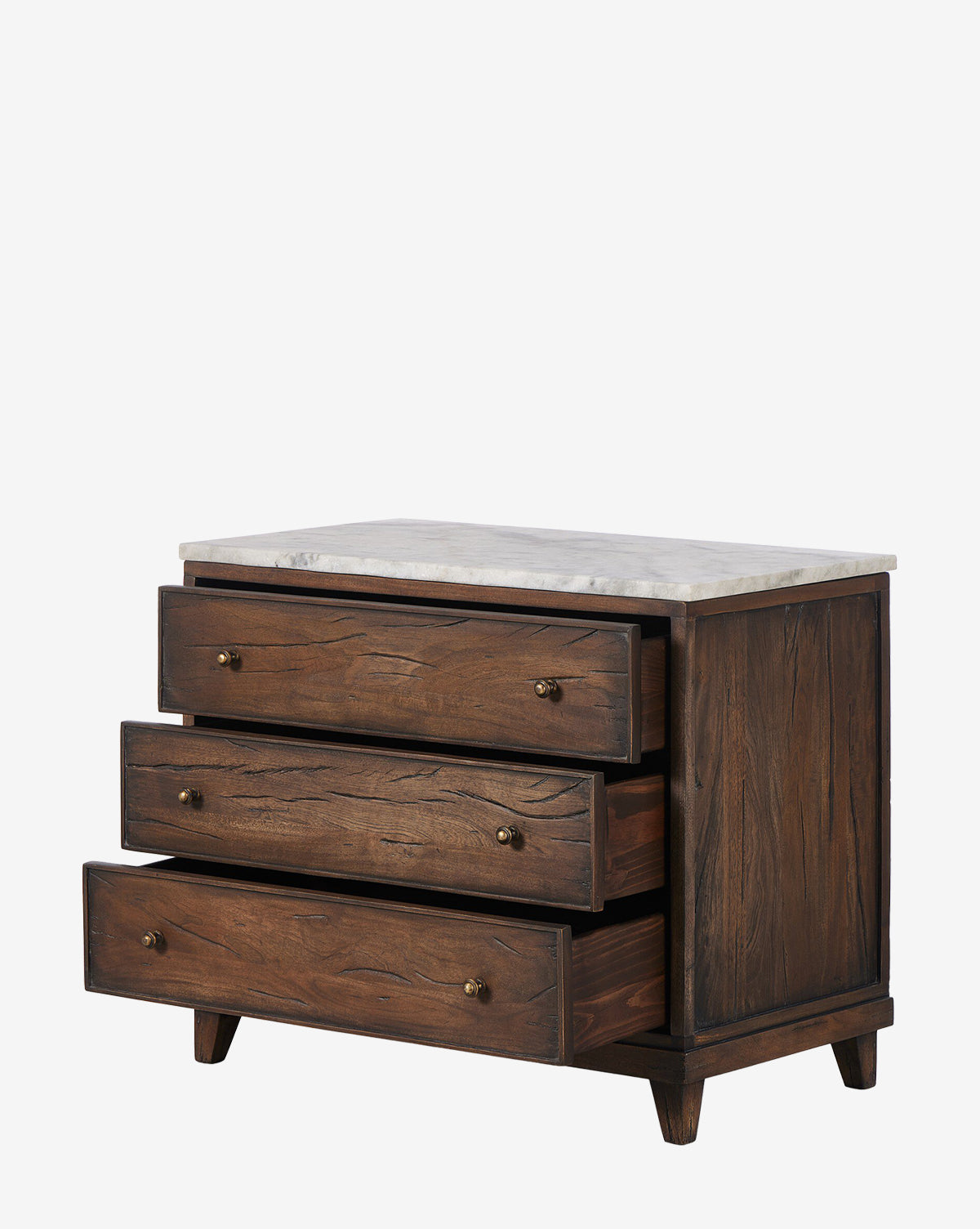 The Bettiga Nightstand is crafted from antique reclaimed wood with a dark finish, features three partially open drawers with brass hardware, and a light marble top, by McGee & Co. Shown against a plain white background.