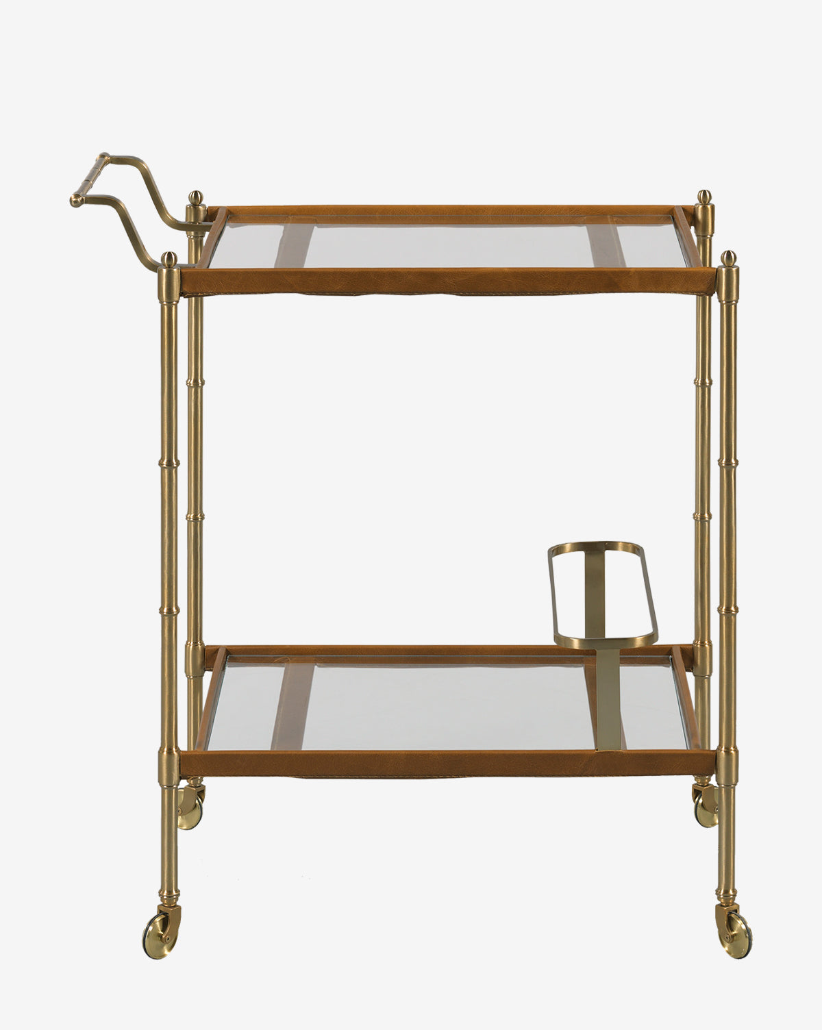 The Bexley Bar Cart showcases a brass bamboo-style frame, two glass shelves, a left-side handle, a metal bottle holder underneath, and four caster wheels for effortless movement, by McGee & Co.
