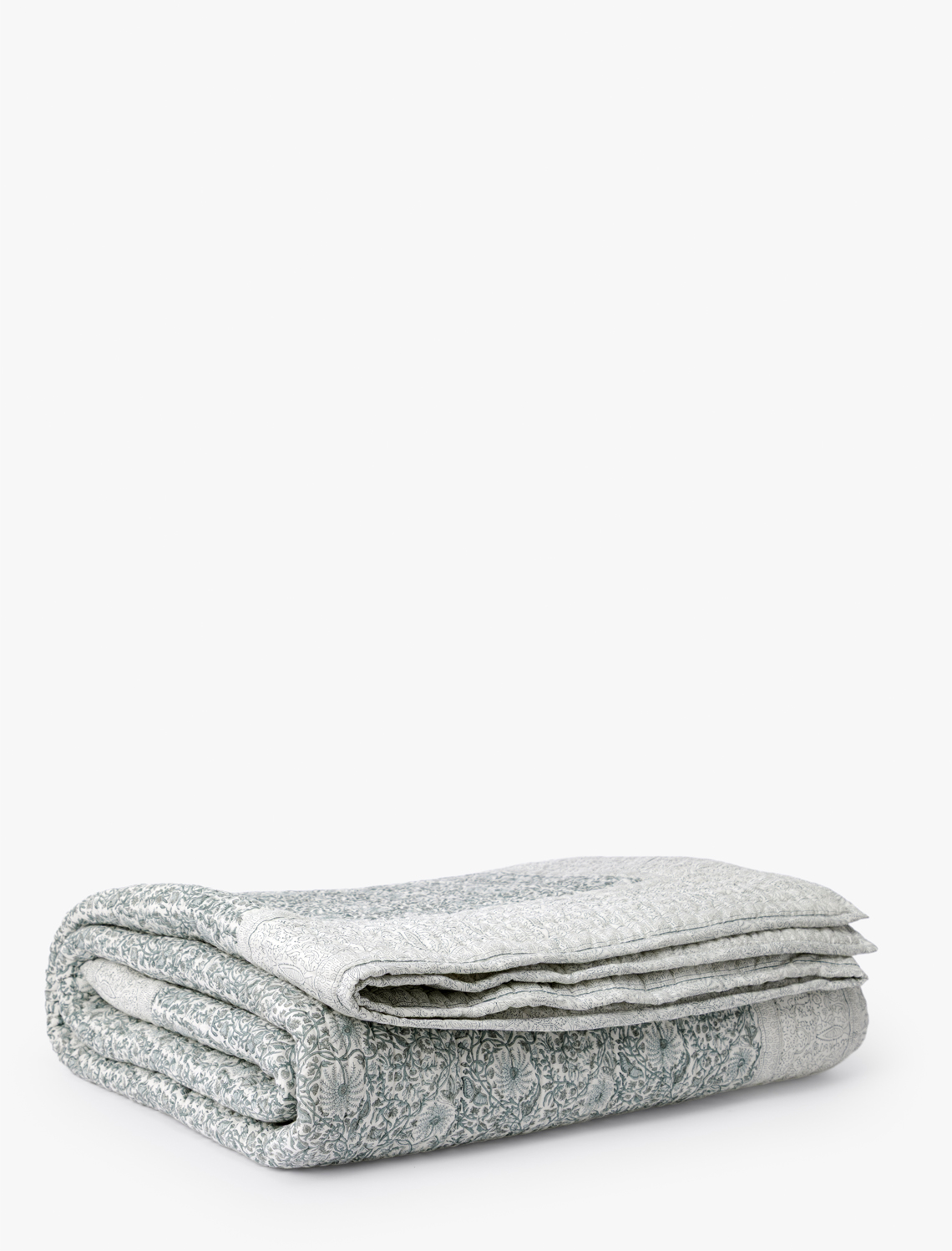 The Blue Floral Block Print Quilt, featuring a neatly folded design and subtle floral motifs, is displayed on a white background—perfect for bringing artisanal charm to your bedding, by McGee & Co.