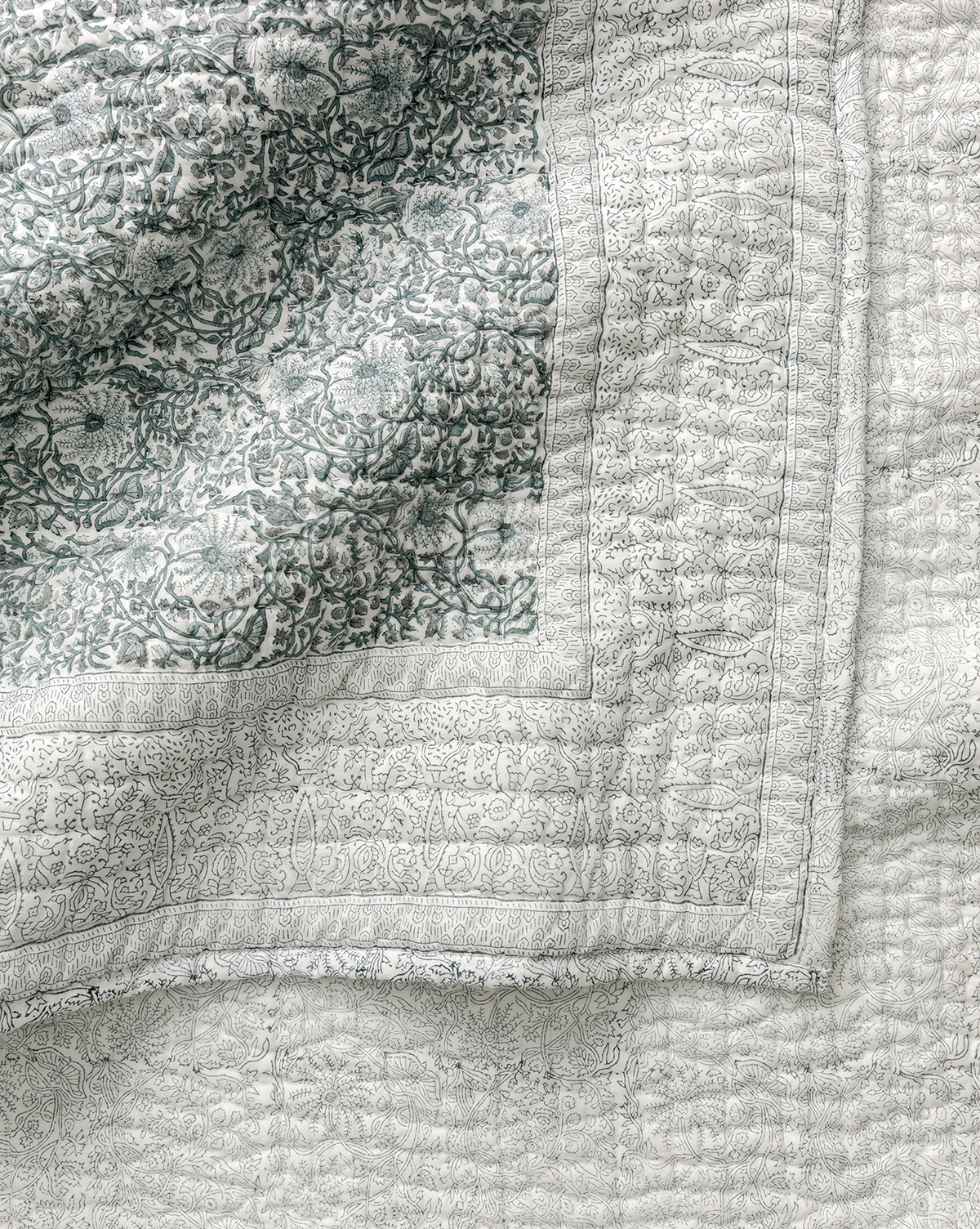 A close-up of the Blue Floral Block Print Quilt, showcasing detailed floral and geometric patterns in soft blue and white, with visible stitching and textured fabric—ideal for fans of artisanal bedding, by McGee & Co.