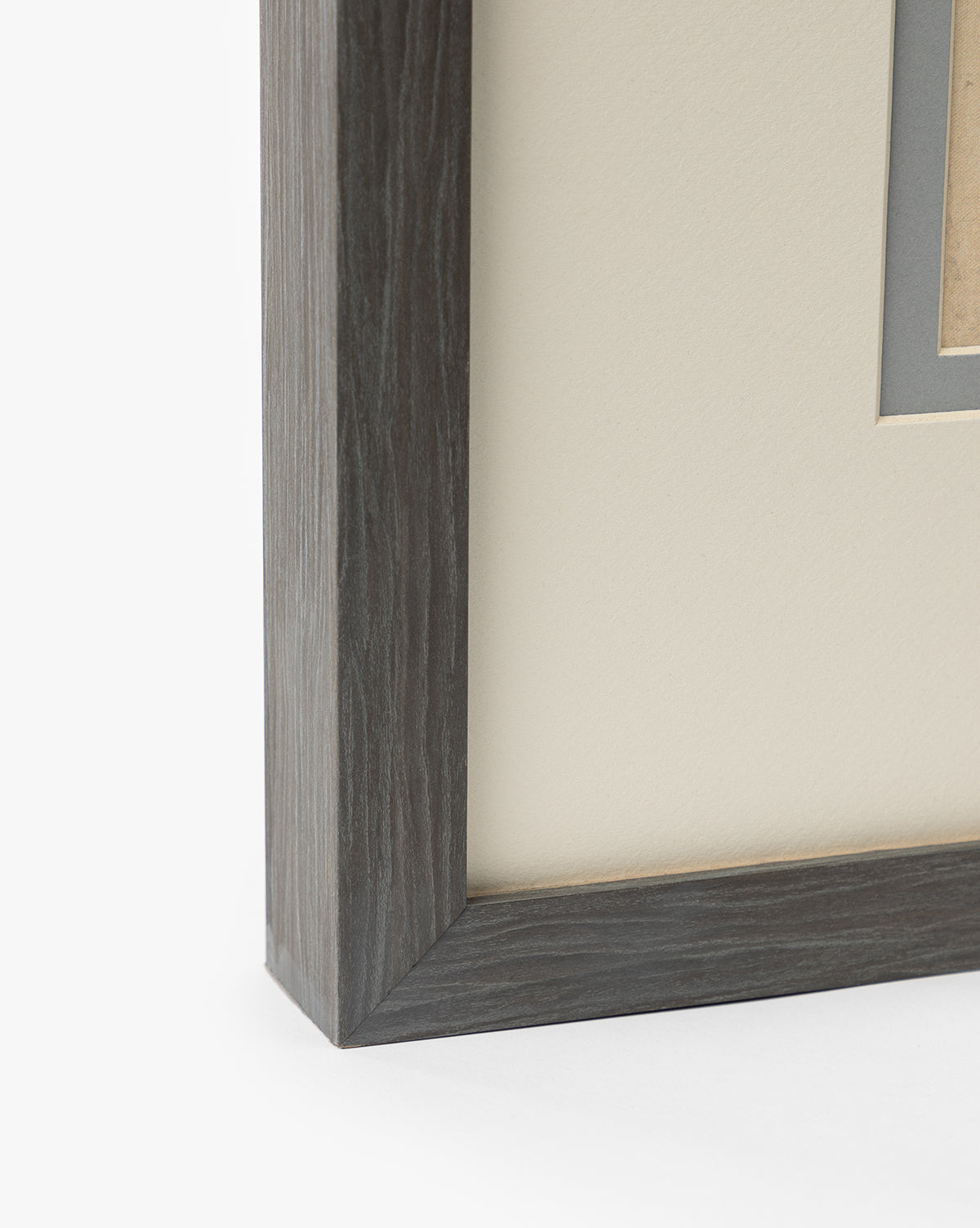 Close-up of a charcoal woodgrain frame’s corner with cream mat and gray inner border, designed to showcase Blue Fruits prints, set against a white background, by McGee & Co.