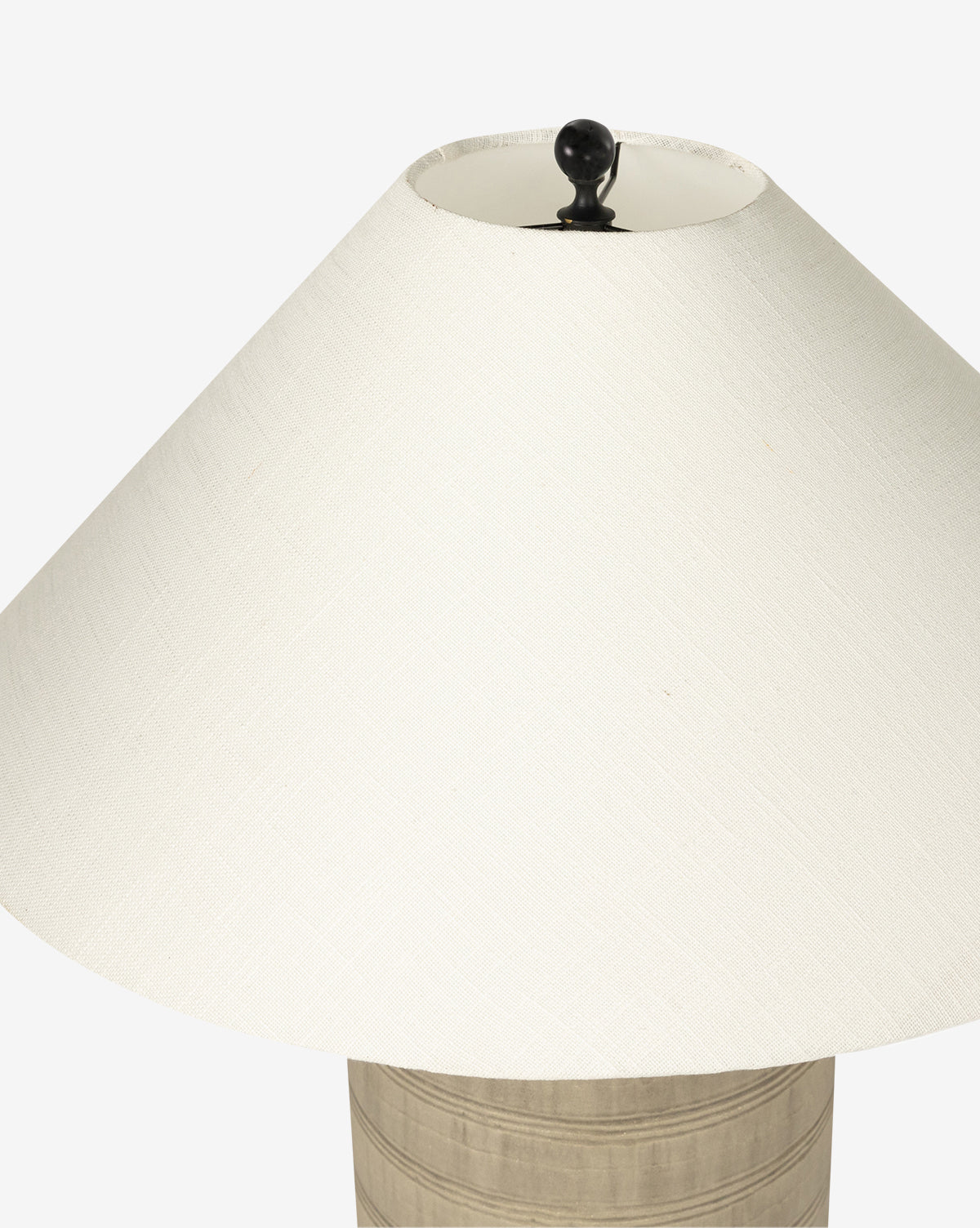 A close-up of the Brynner Table Lamp, featuring a wide cream fabric shade with a round black finial and a light base accented by subtle horizontal lines—perfect for complementing transitional decor, by McGee & Co.