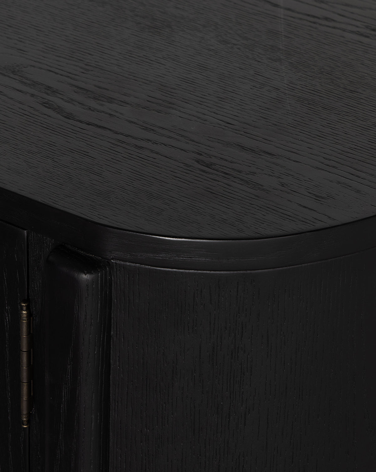 Close-up of the Burton Sideboards corner, showcasing dark oak wood grain, rounded edges, and a brass hinge on the left by McGee & Co.