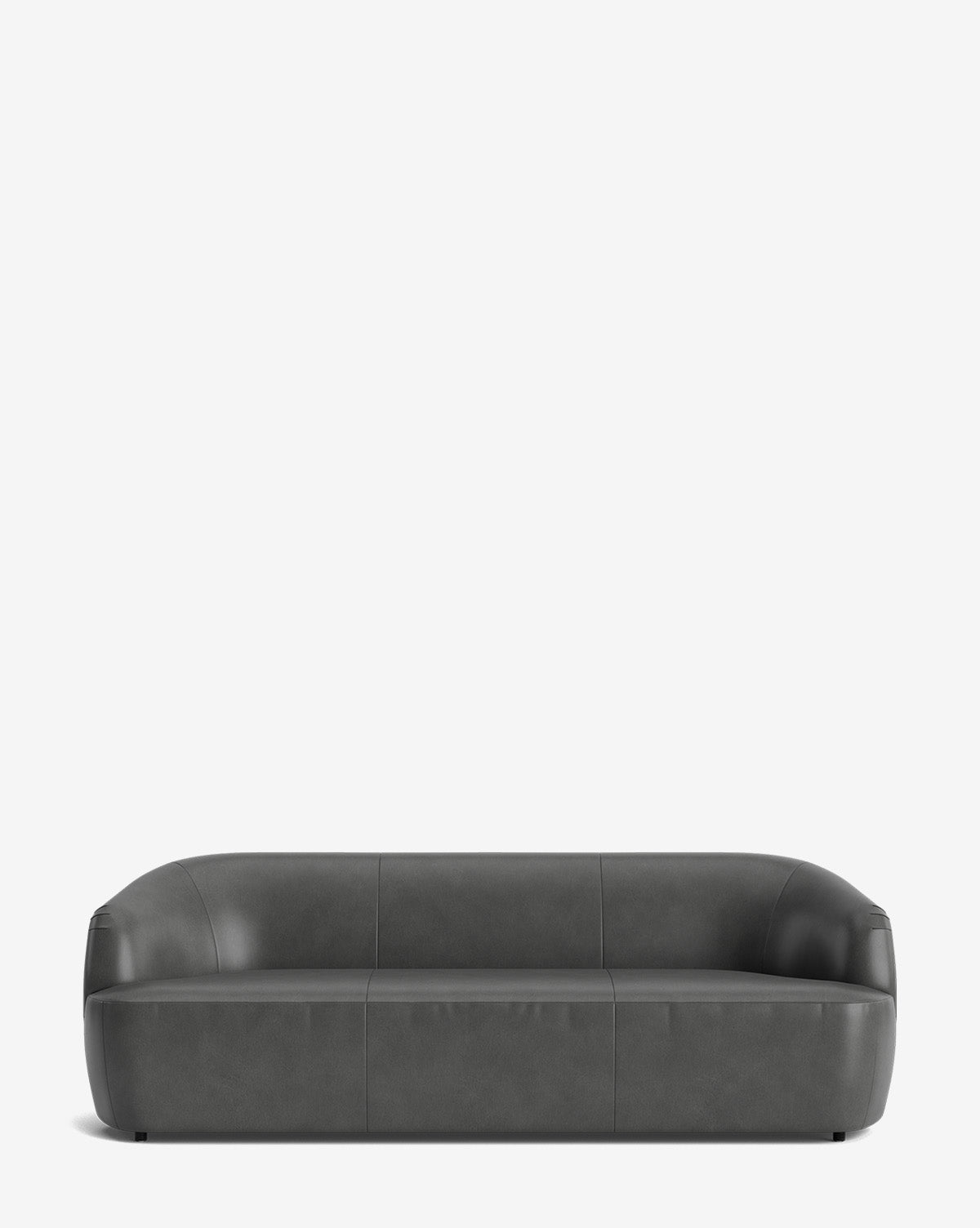 The Byron Sofa 96 is a modern, dark gray leather sofa with a low back and rounded edges set against a white background. This minimalist piece has smooth surfaces, no visible legs, and highlights a refined curved back design by McGee & Co.