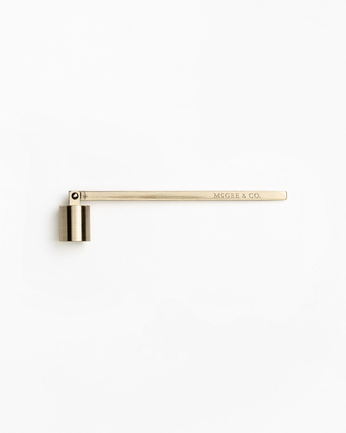 A brass-colored Candle Snuffer, a must-have candle accessory with “MCGEE & CO.” engraved on the handle, placed on a white background.