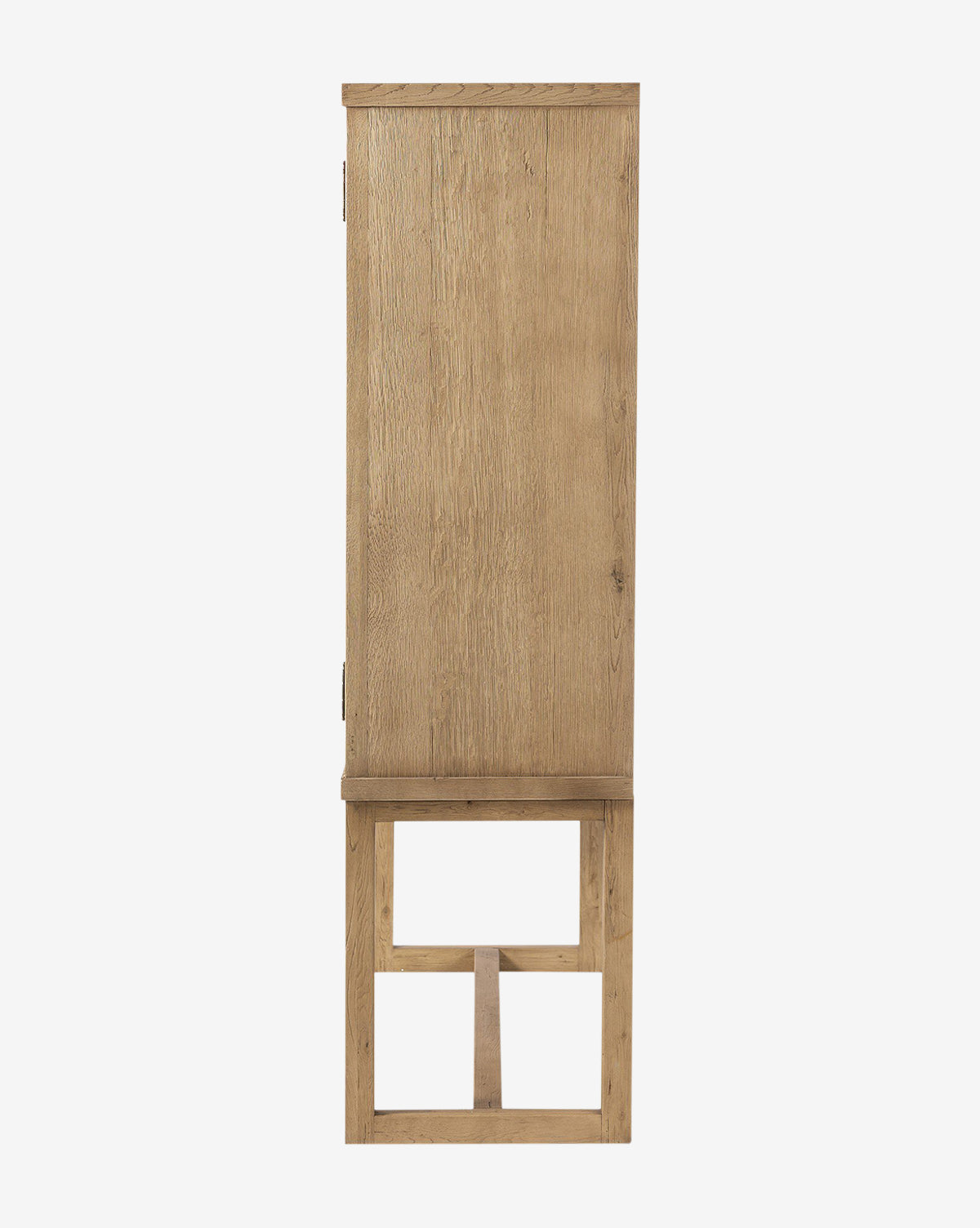 A side view of the Carrington Cabinet, a tall rectangular piece in worn oak with bronze-finished hardware, standing on a wooden base featuring an open geometric design by McGee & Co.