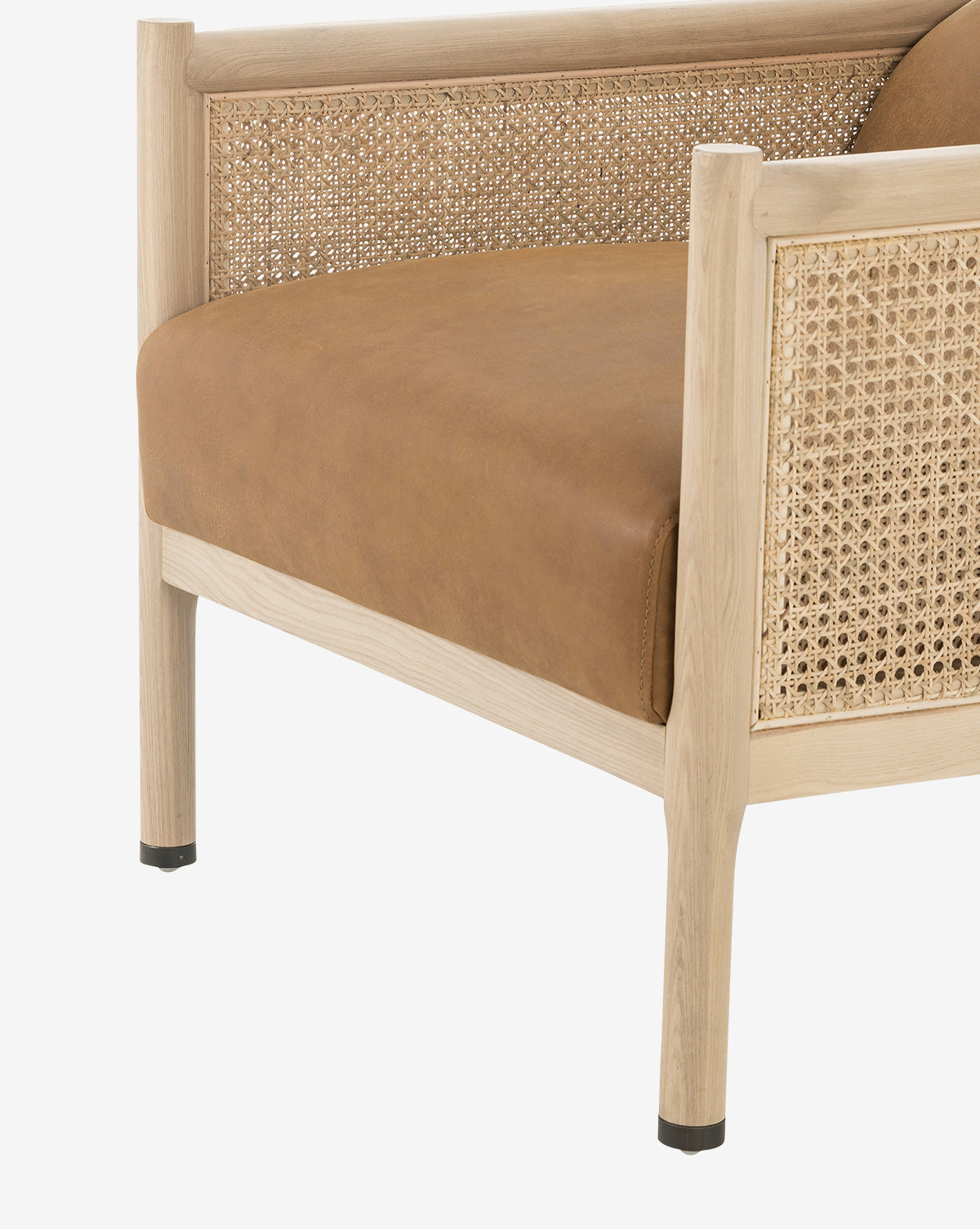 A close-up of the Channing Lounge Chair corner highlights its light wood frame, woven rattan panels, and high-performance upholstered seat cushion, exemplifying refined Parisian design against a white background, by McGee & Co.