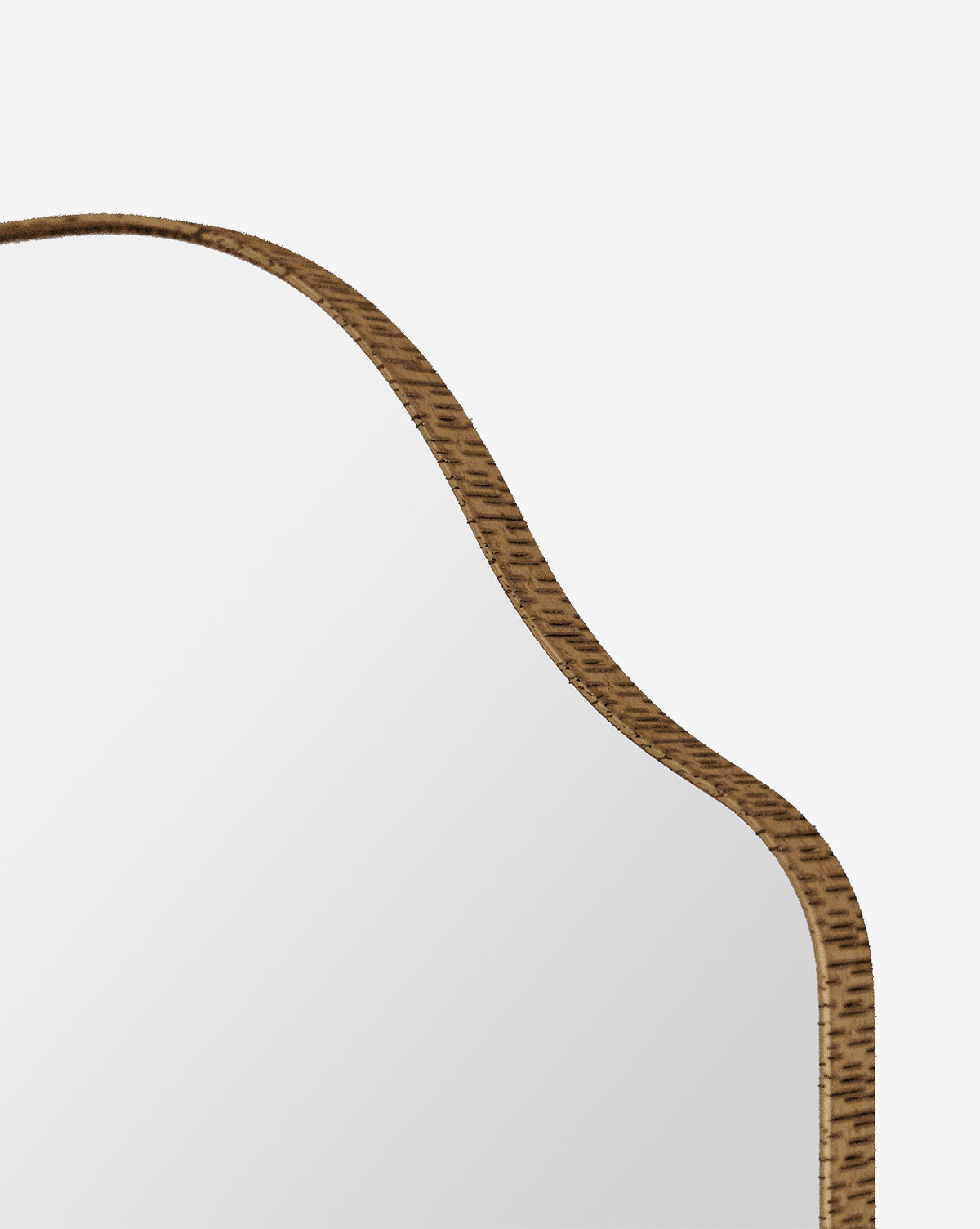 Close-up of the Chiara Mirrors top corner showcases its wavy, arched wooden frame in an antique brass finish against a plain white background—a striking blend of modern and traditional design, by McGee & Co.