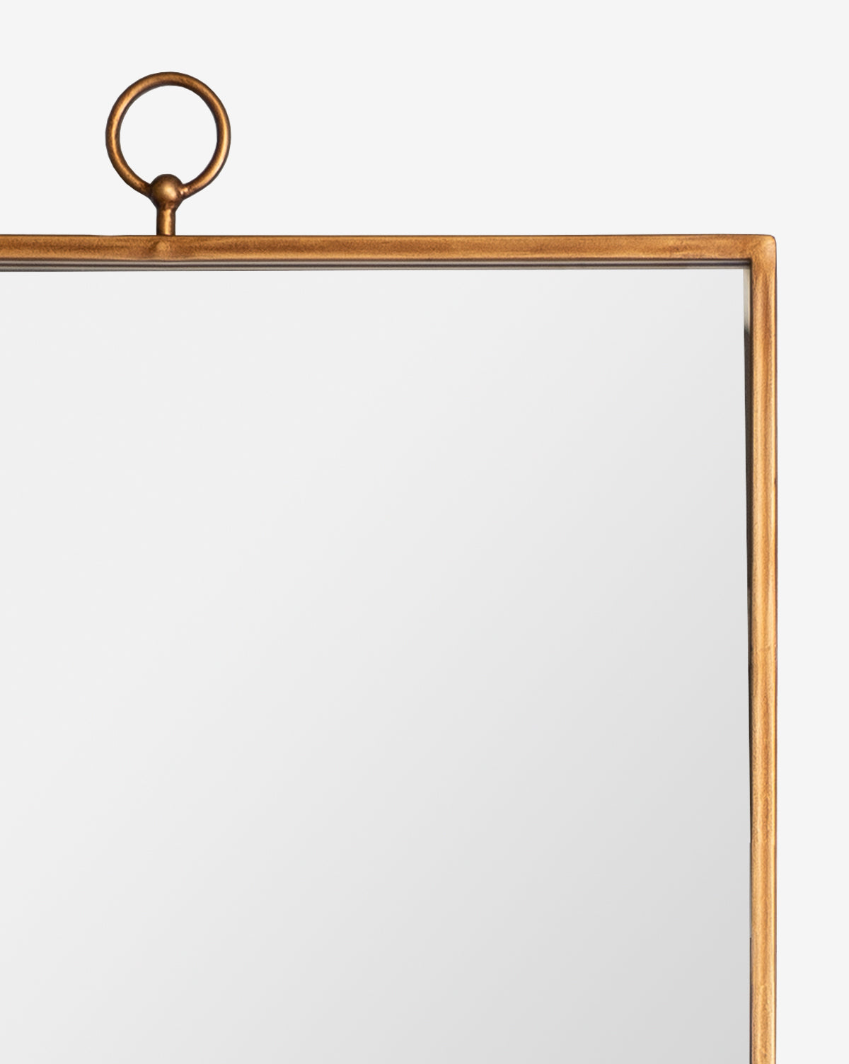 A partial view of the Cleda Floor Mirror, featuring a classic design with a thin gold metal frame and a circular ring at the top center, set against a plain white background, by McGee & Co.