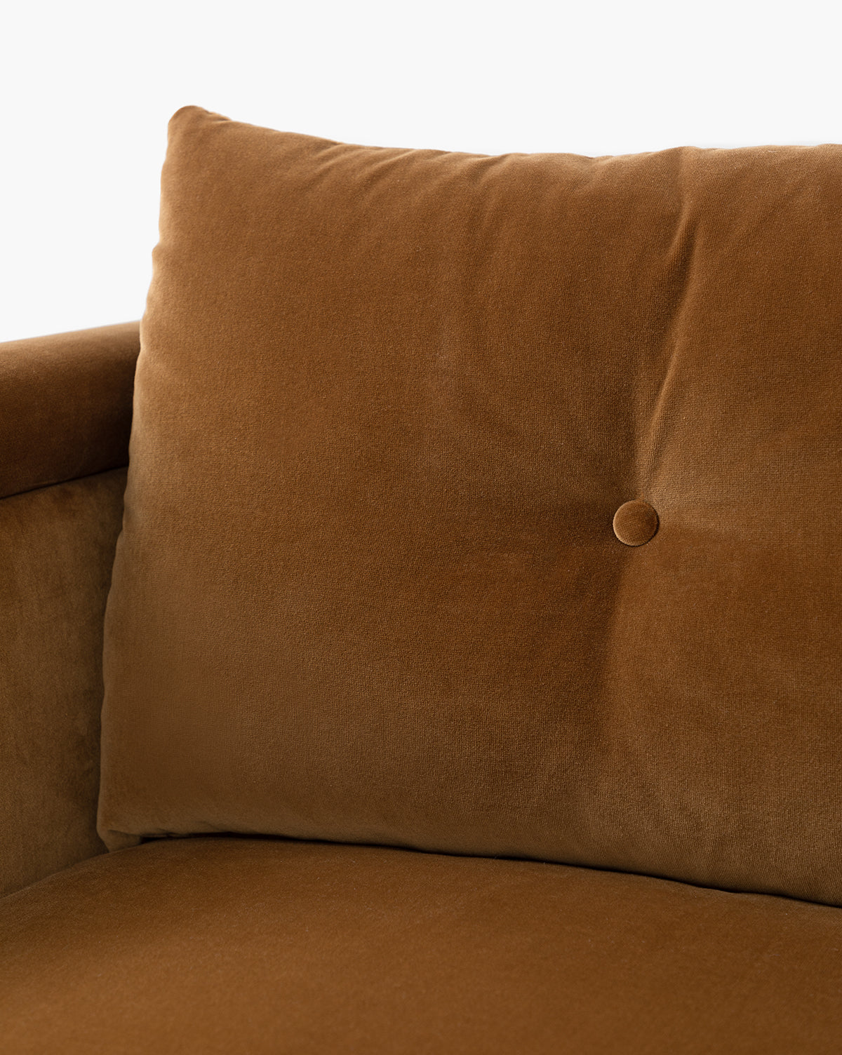 Close-up of the Clegg Lounge Chairs plush brown cotton velvet upholstery, featuring a single centered button tuft and soft, smooth texture. The plain light background highlights the chair’s rich color, by McGee & Co.