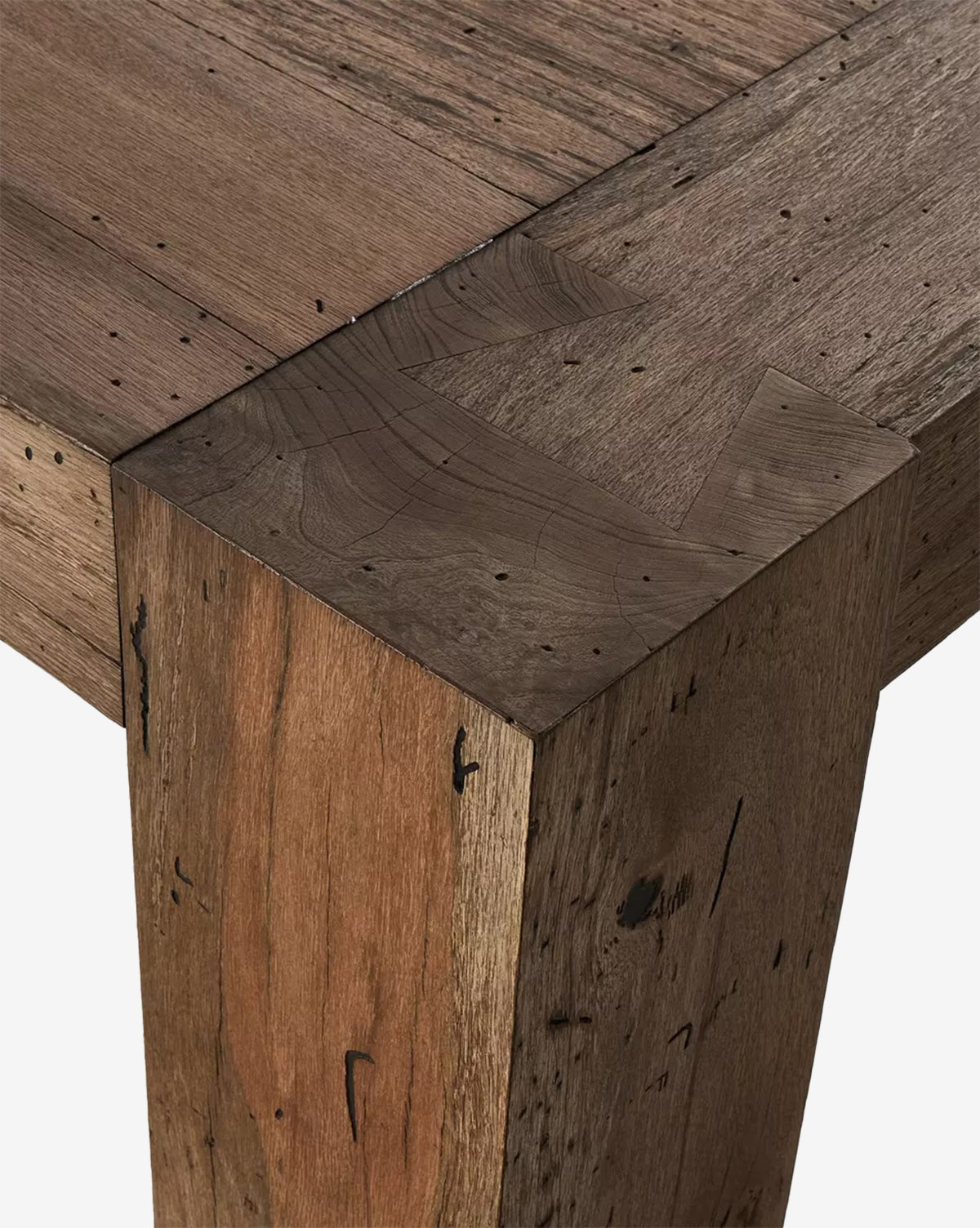 Close-up of a corner of the Clellan Dining Table, highlighting its natural wood grain, knots, and imperfections. The sturdy leg and smooth rectangular top with visible joinery emphasize contemporary craftsmanship by McGee & Co.