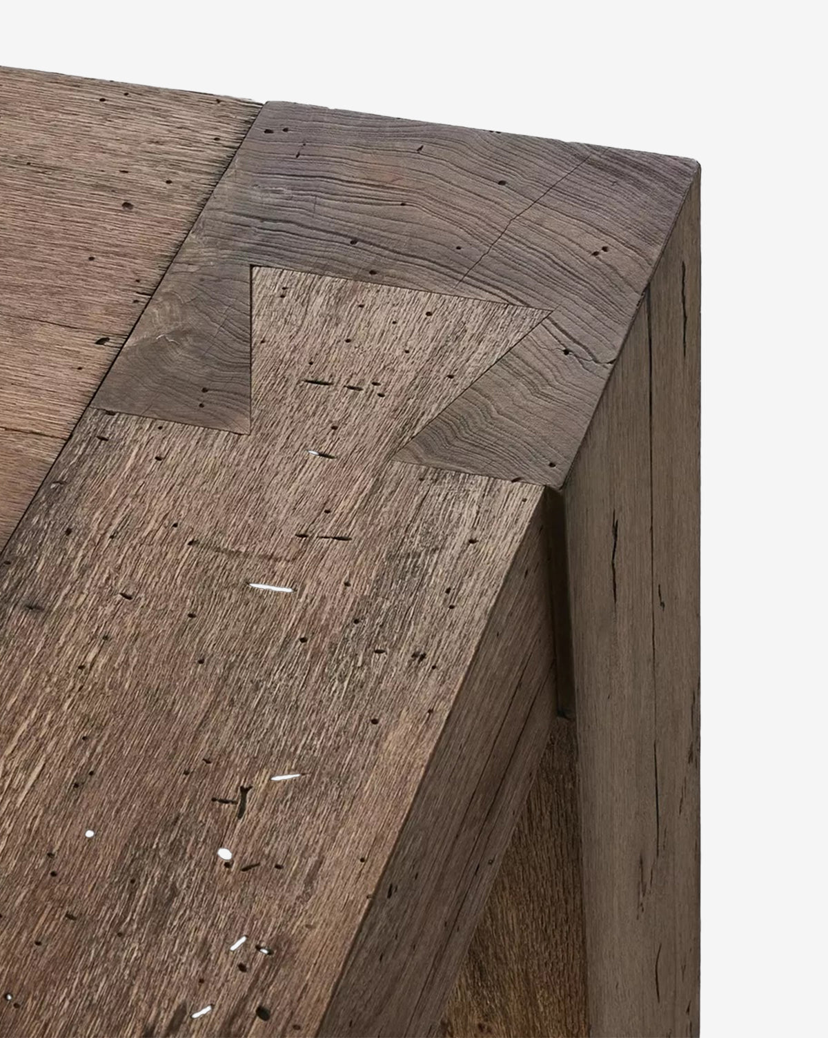 Close-up of the Clellan Dining Table’s geometric corner, highlighting arrow-shaped joinery and visible natural wood grain with small holes and imperfections, by McGee & Co.
