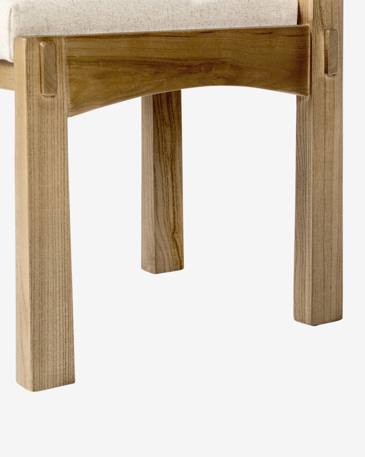 Close-up of the Cyprian Dining Chair leg in light wood and a beige performance fabric seat showcases its simple, sturdy craftsmanship—ideal for any dining room—set against a plain white background, by McGee & Co.