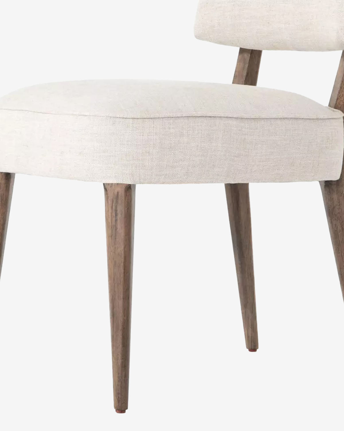 A close-up of the Cyrene Dining Chair showcases its ivory performance fabric seat and backrest, angled wood legs, and minimalist design, by McGee & Co.