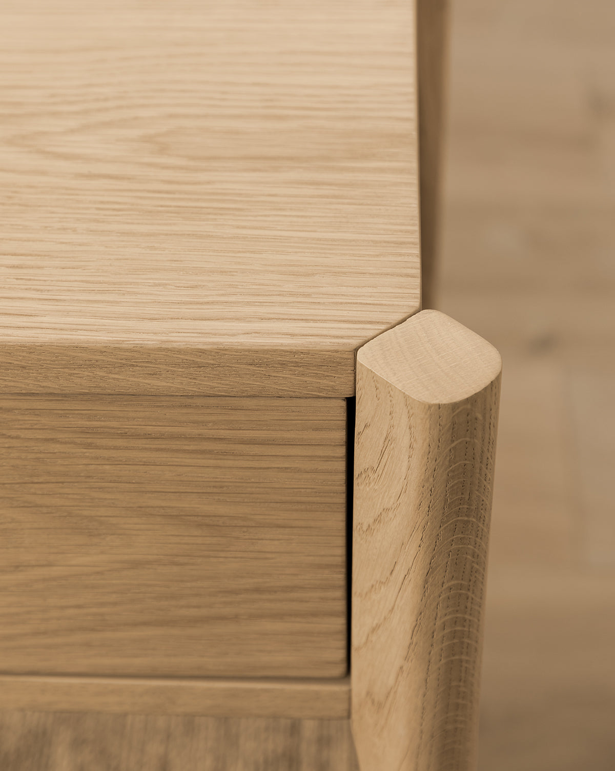 Close-up of the Dana 2-Drawer Console’s corner, highlighting smooth, rounded edges and detailed wood grain—an elegant accent for entryway decor against a matching wooden backdrop, by McGee & Co.