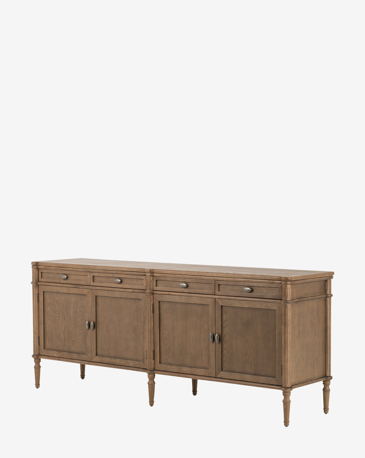 The Dixon Sideboard features four drawers and four cabinet doors in oak wood with a natural finish, aged brass hardware, and turned legs, shown against a plain white background by McGee & Co.