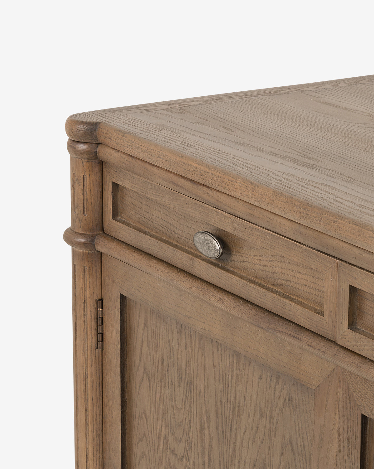 A close-up of the Dixon Sideboard’s corner, highlighting its oak wood grain, a drawer with aged brass hardware, and a door below that showcases fine craftsmanship, by McGee & Co.