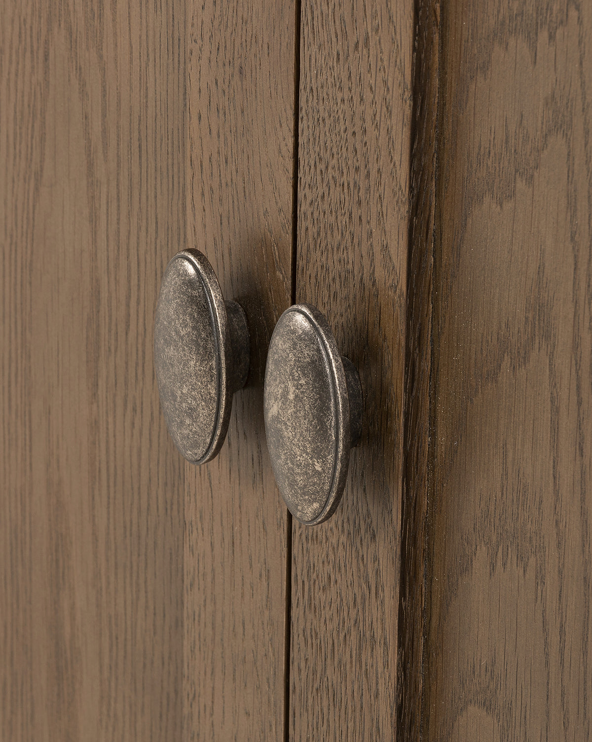 Close-up of two oval-shaped aged brass cabinet handles on natural brown wood doors, ideal for enhancing the classic Dixon Sideboard by McGee & Co.