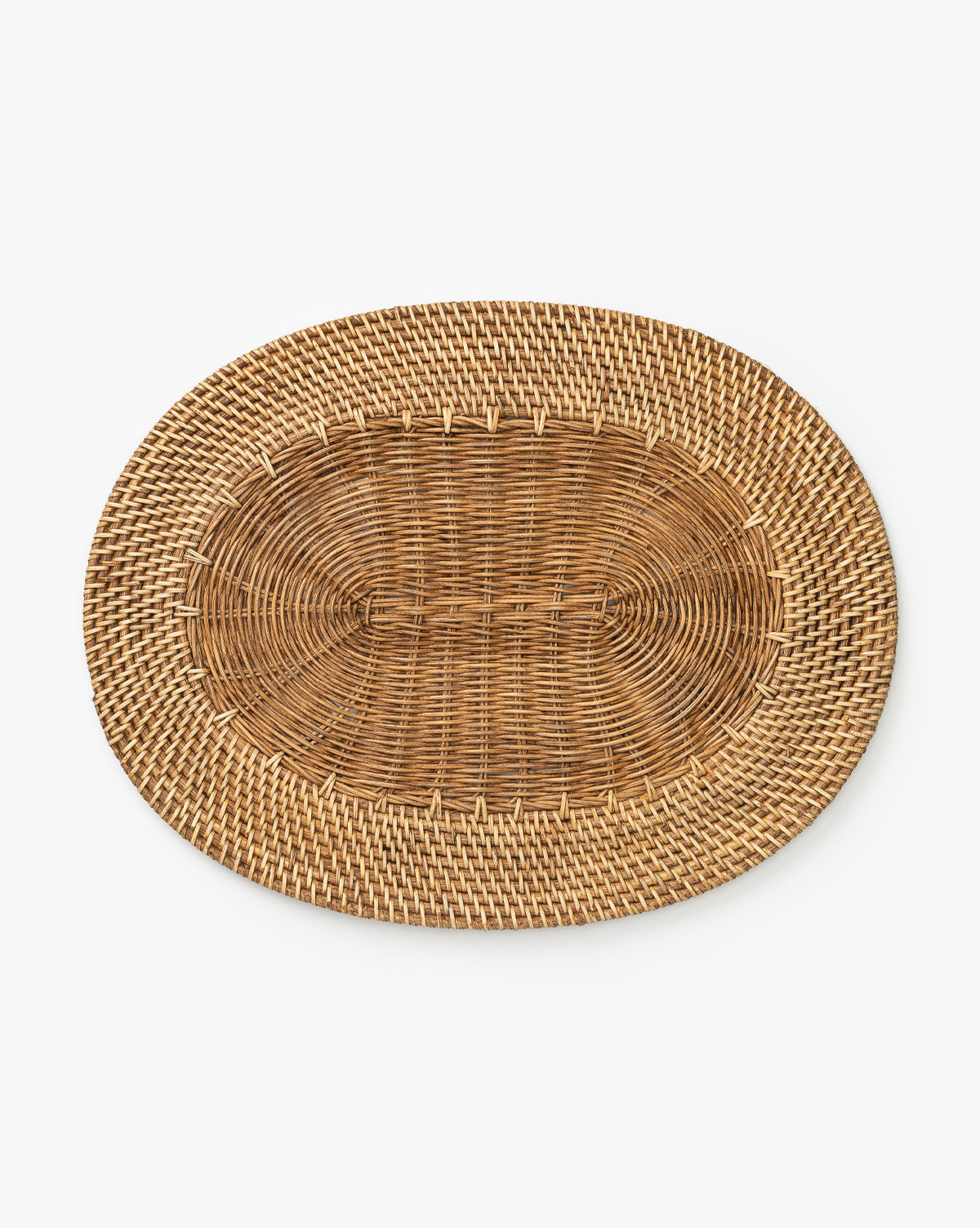 The Davin Placemat is an oval woven rattan tray in natural brown with an intricate basketweave pattern, also usable as a wicker placemat, shown on a plain white background by McGee & Co.