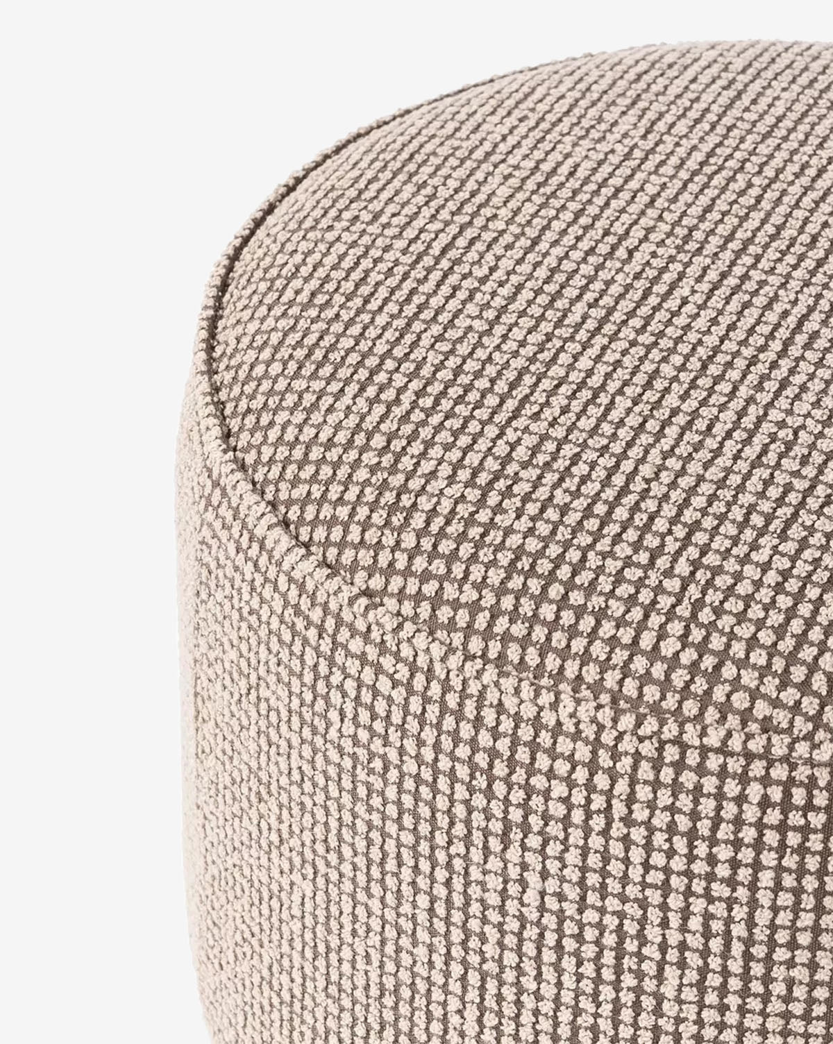 Close-up of the Dawson Ottomans upper edge, showing its beige upholstery with a subtle dotted and striped pattern. This round ottoman features a textured finish and comfortable cushion, set against a white background, by McGee & Co.