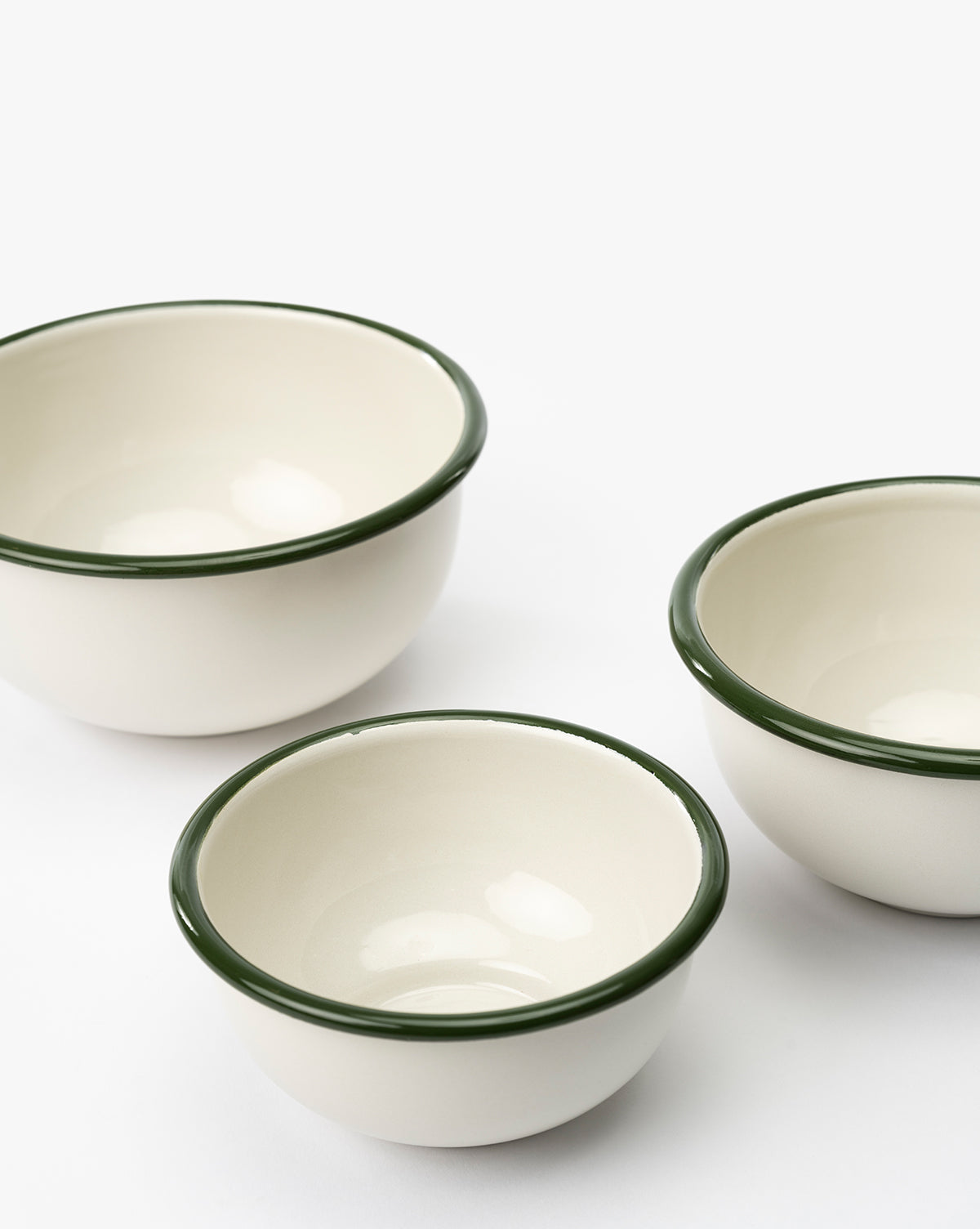 The Delia Bowls (Set of 3) features white stoneware bowls with dark green rims, arranged in a triangular layout on a white surface—these vintage-inspired bowls are empty, perfect for serving or display, by McGee & Co.