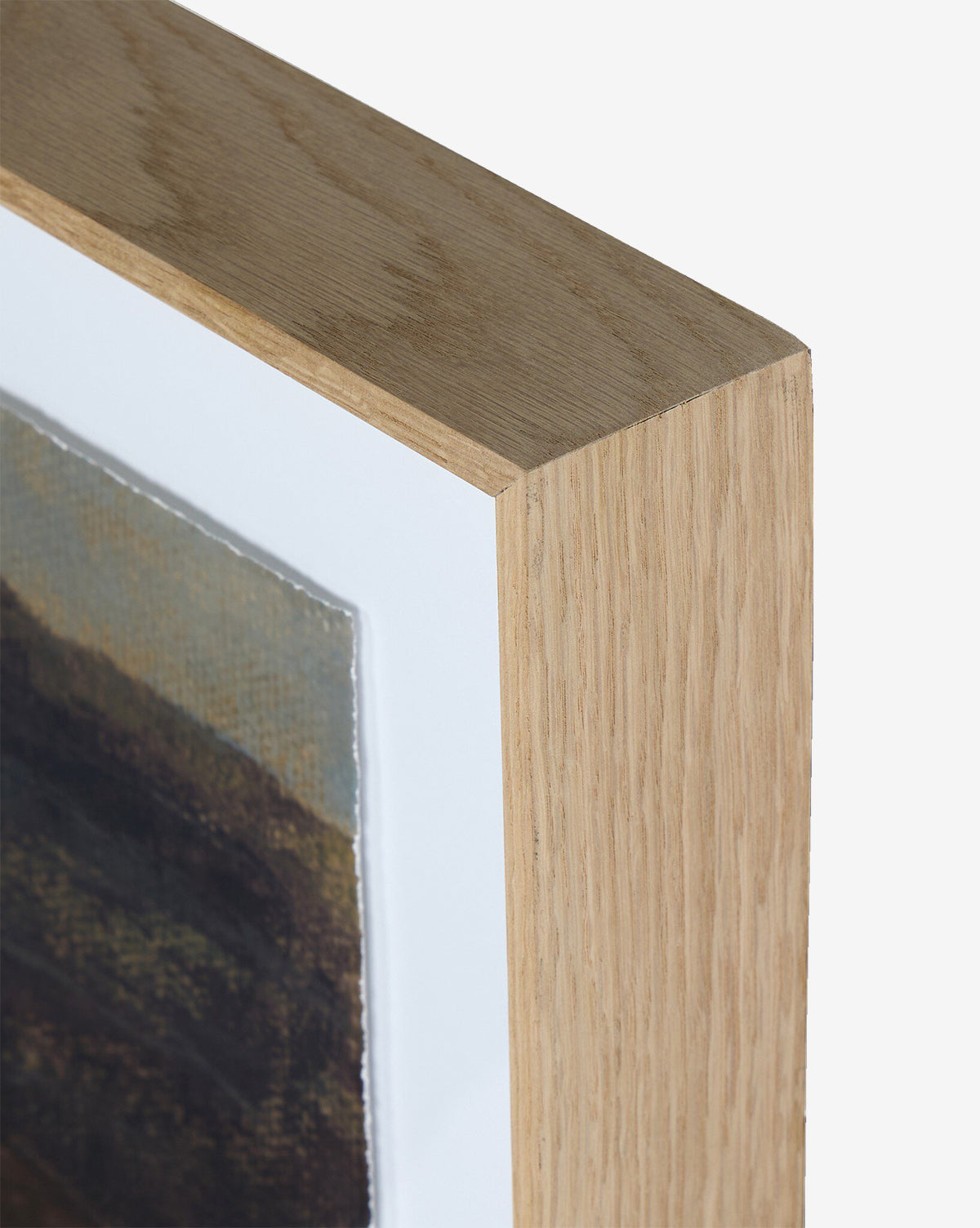 Close-up of the top corner of a white oak frame with a white mat, featuring Desert Hues I by Aileen Fitzgerald printed on fine art paper, by McGee & Co. The background is plain white.