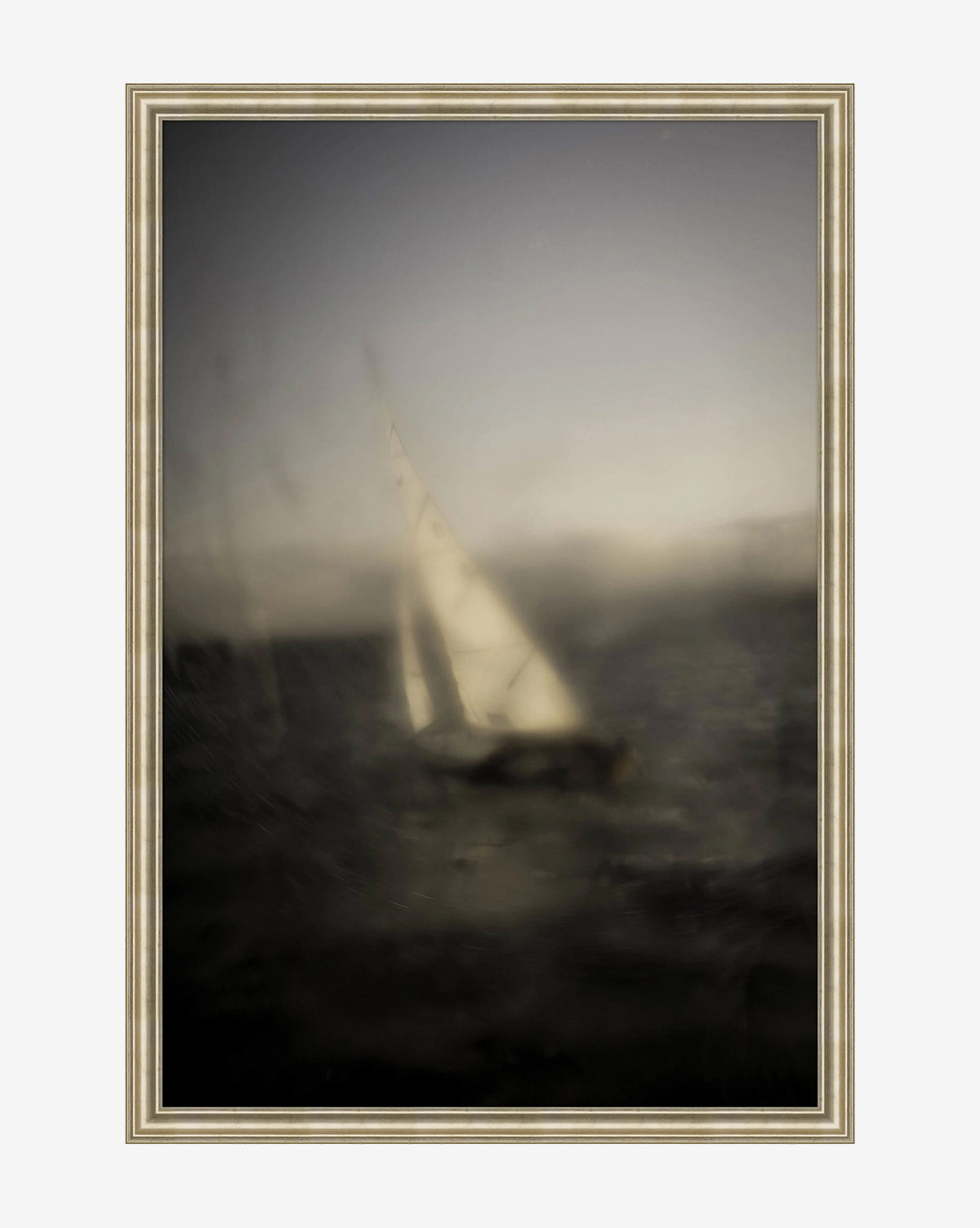 Drifting Sails by Susan Currie is a framed art piece featuring a softly blurred sailboat with a white sail on dark water under a cloudy sky, offering a dreamy, impressionistic look ideal for abstract wall art lovers, by McGee & Co.