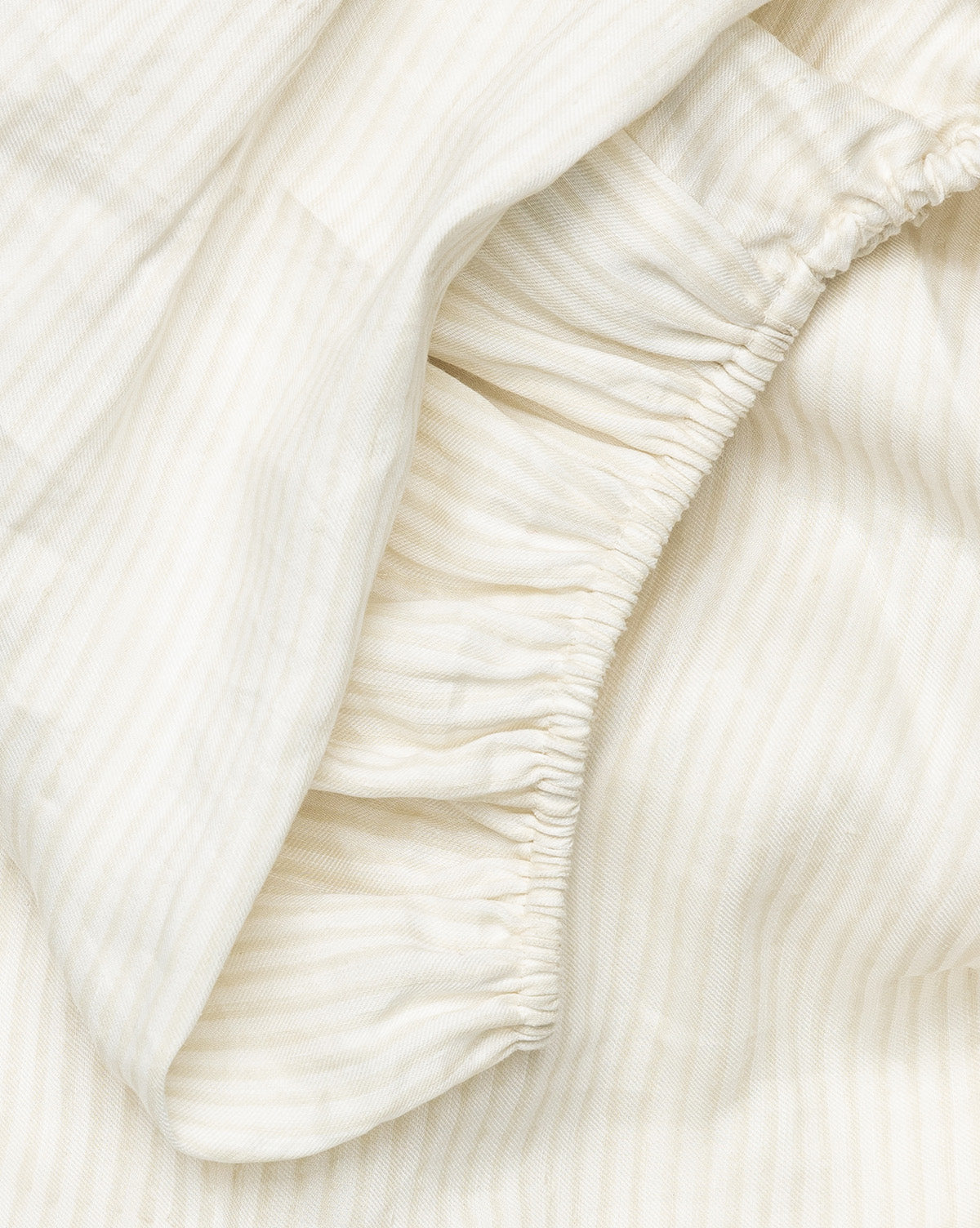 Close-up of the Easton Crib Sheet in light beige with subtle stripes and gathered elastic, showing its soft texture—an inviting and cozy choice for your babys crib bedding.