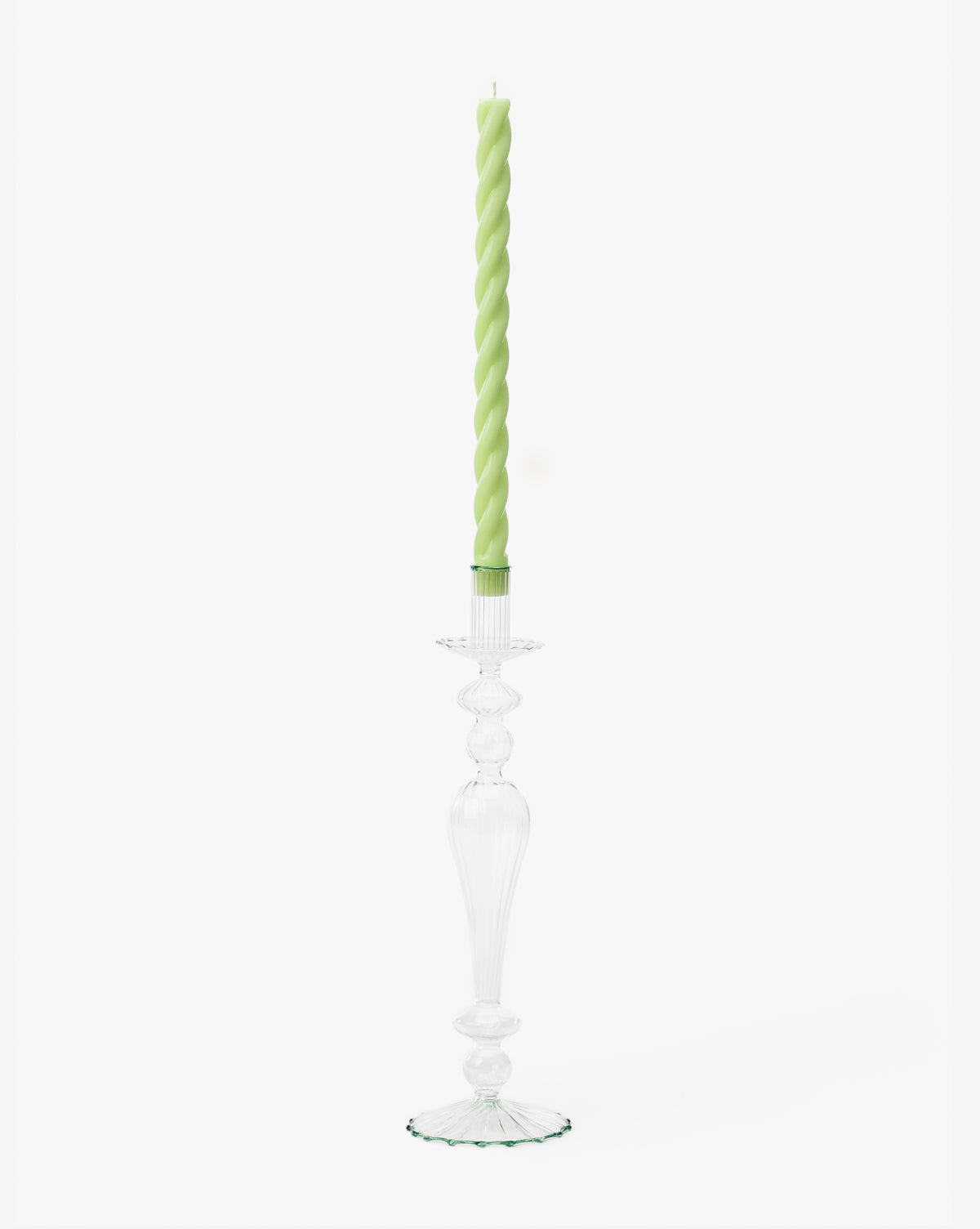 A tall, clear glass taper holder with a decorative design holds a light green twisted candle against a plain white background, resembling the McGee & Co. x Loeffler Randall Effie Taper Holder by McGee & Co.