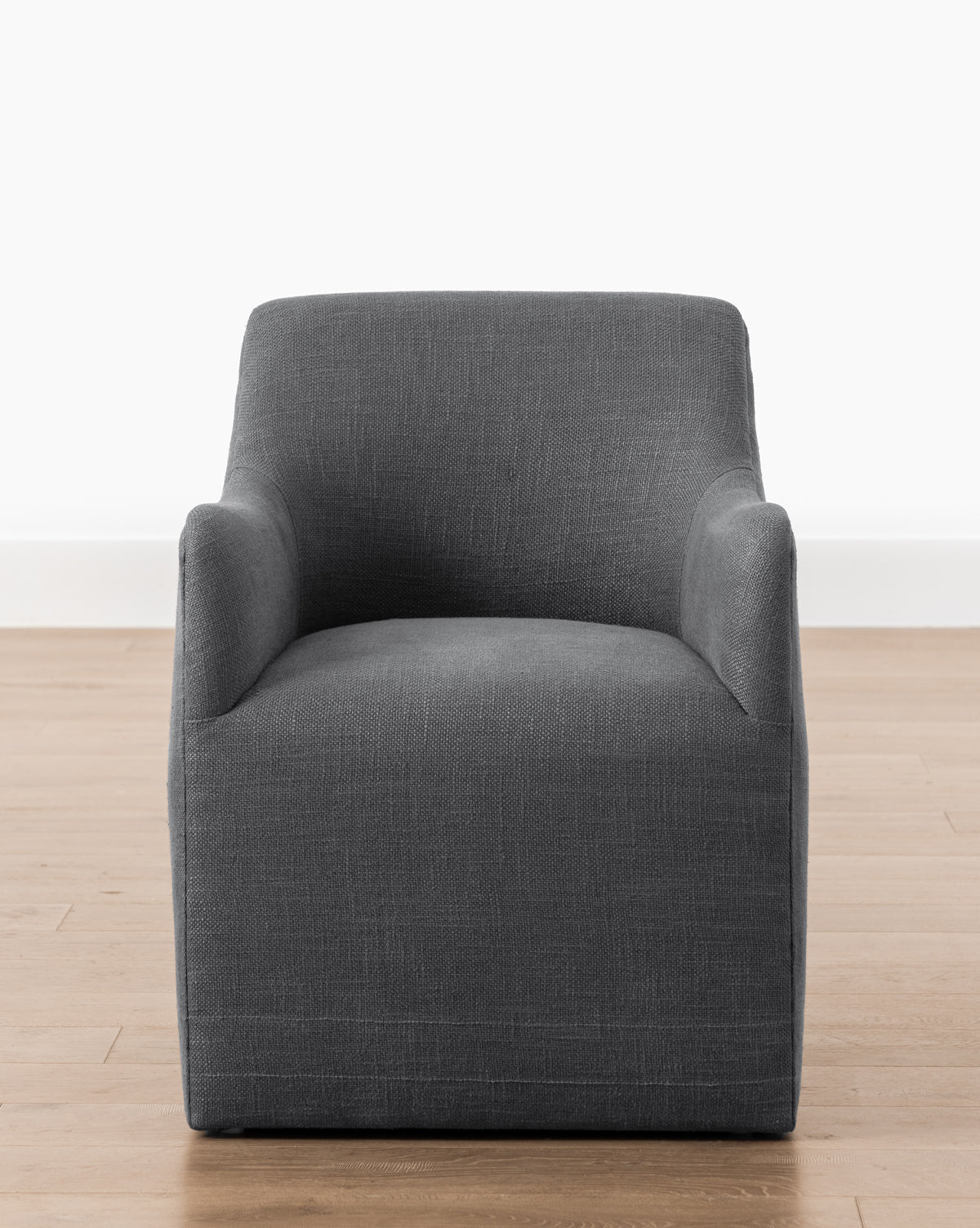 The Elton Dining Chair features a modern, boxy design with curved armrests, upholstered in dark gray linen blend—an elegant choice for contemporary dining areas, by McGee & Co.