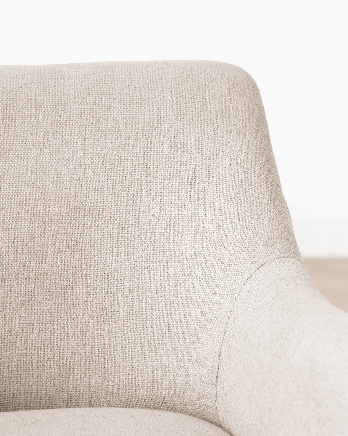 Close-up of the Elton Dining Chair’s upper section, featuring a curved backrest and armrest in light beige linen-blend upholstery—an elegant addition to modern dining spaces, by McGee & Co.