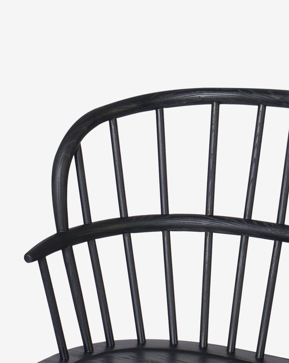Close-up of the curved backrest on a black wooden chair, with vertical spindles and a sleek design—mirroring the refined style and sturdy ash frame of the Elysia Bench—set against a plain white background, by McGee & Co.