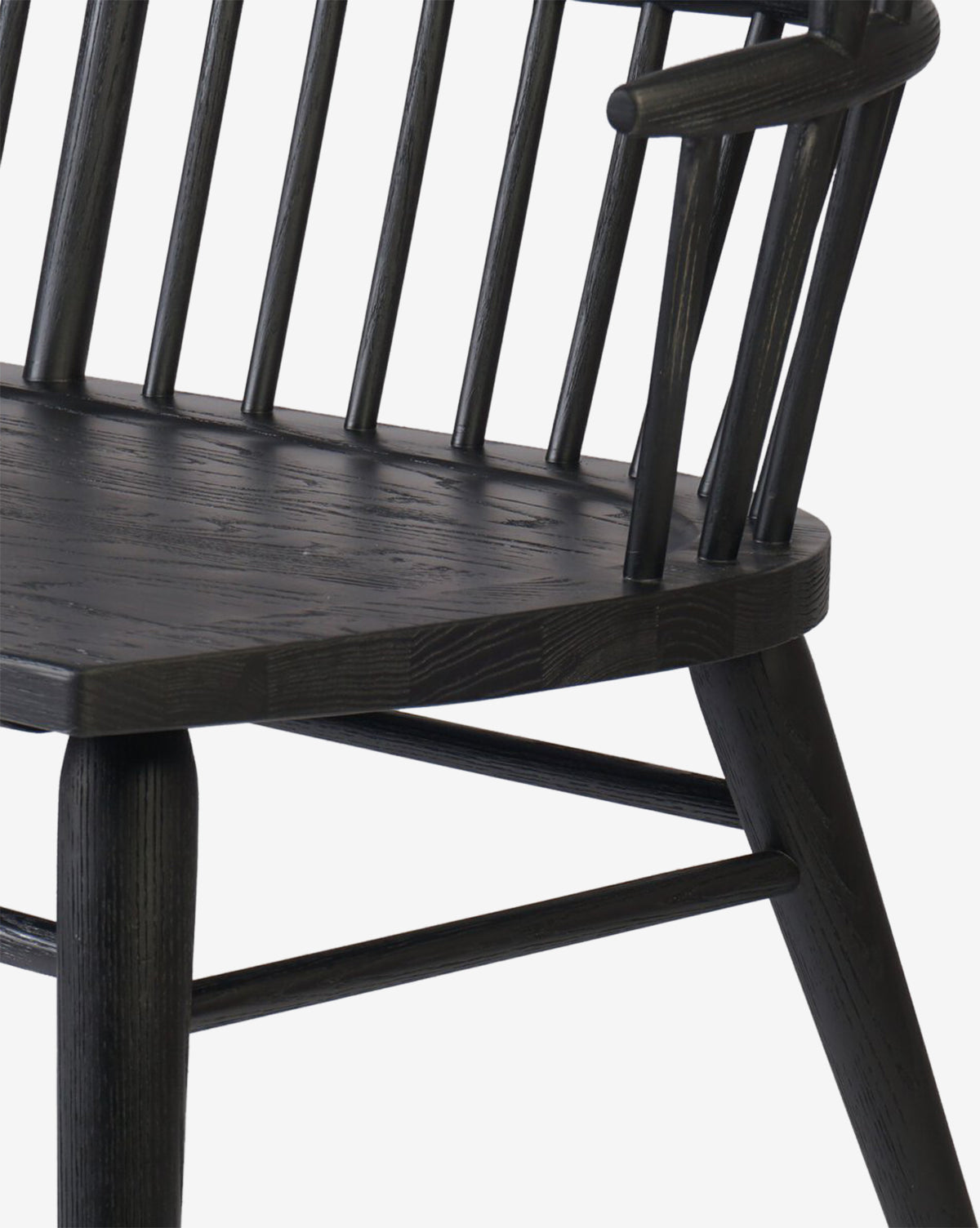 A close-up of a dark wooden chair with a spindle backrest, angled seat, and rounded legs on white background, highlighting details reminiscent of the Elysia Bench’s solid ash frame, by McGee & Co.