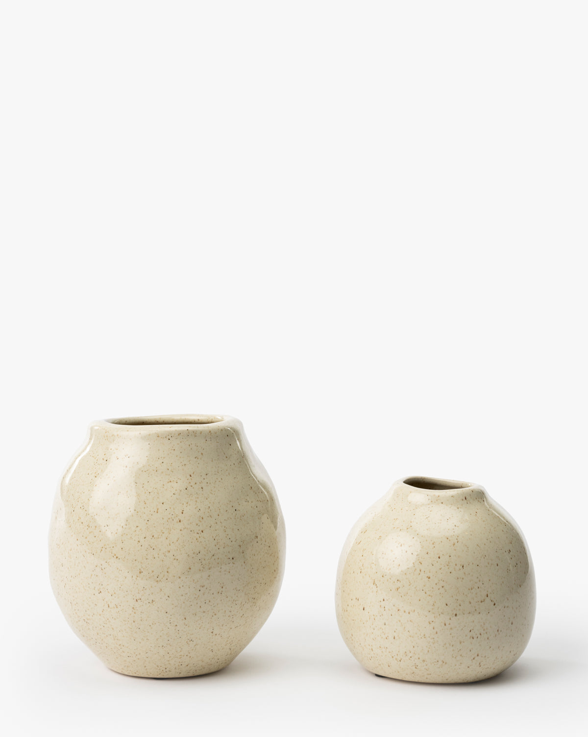 The Erma Bud Vases (Set of 2) feature round, beige ceramic designs with small openings in two different sizes, displayed side by side on a white background by McGee & Co.