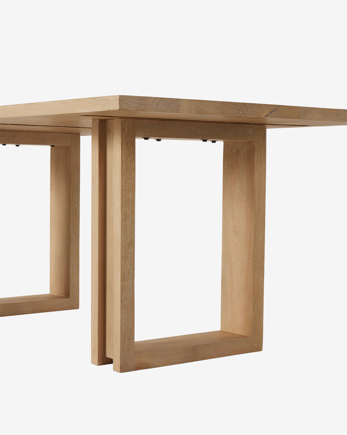 A close-up of the Ernie Dining Table, a modern piece made from solid mango wood featuring a thick rectangular top and geometric open legs, set against a plain white background, by McGee & Co.