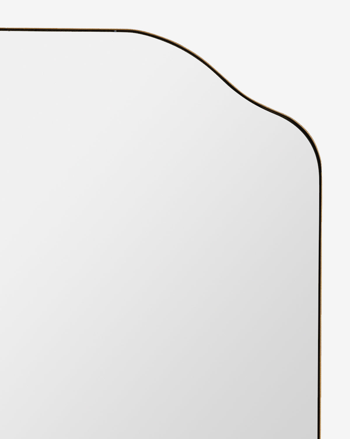Close-up of the top left corner of the Ethel Wall Mirror, featuring a curved and scalloped edge, thin metal frame, and set against a white background, by McGee & Co.