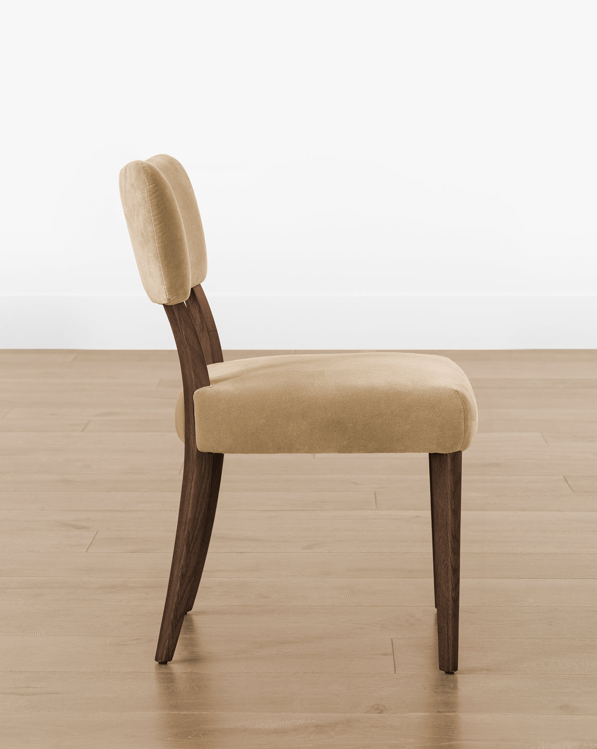 The Etienne Dining Chair (Ready to Ship) features a light beige upholstered seat and backrest with angled dark wooden legs, set on a light wood floor against a white wall—a modern update of the classic vintage dining chair, by McGee & Co.