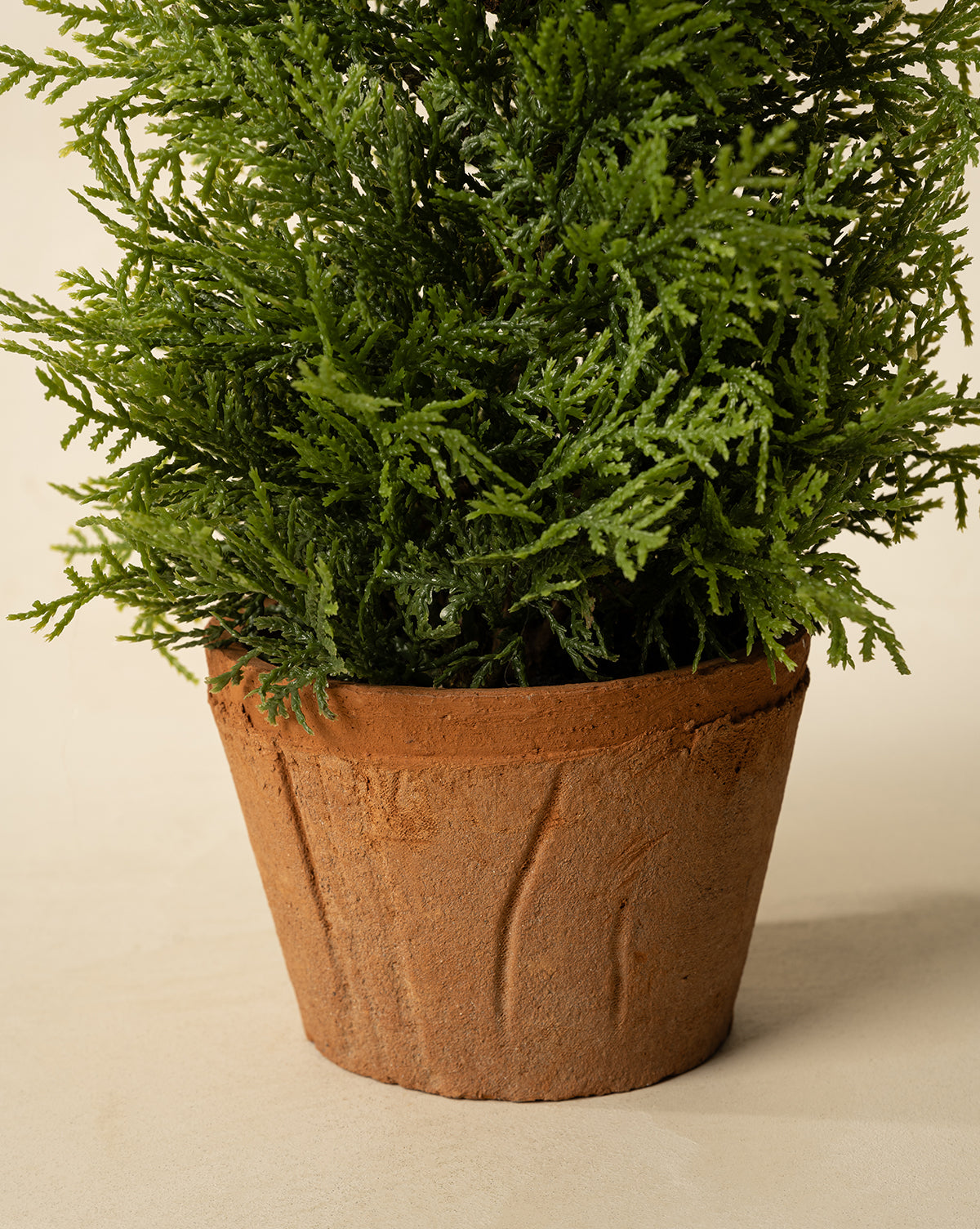 A close-up of the 17" Cypress Faux Potted Tree featuring lush green foliage in a textured brown terracotta pot, set against a plain, light background, by McGee & Co.