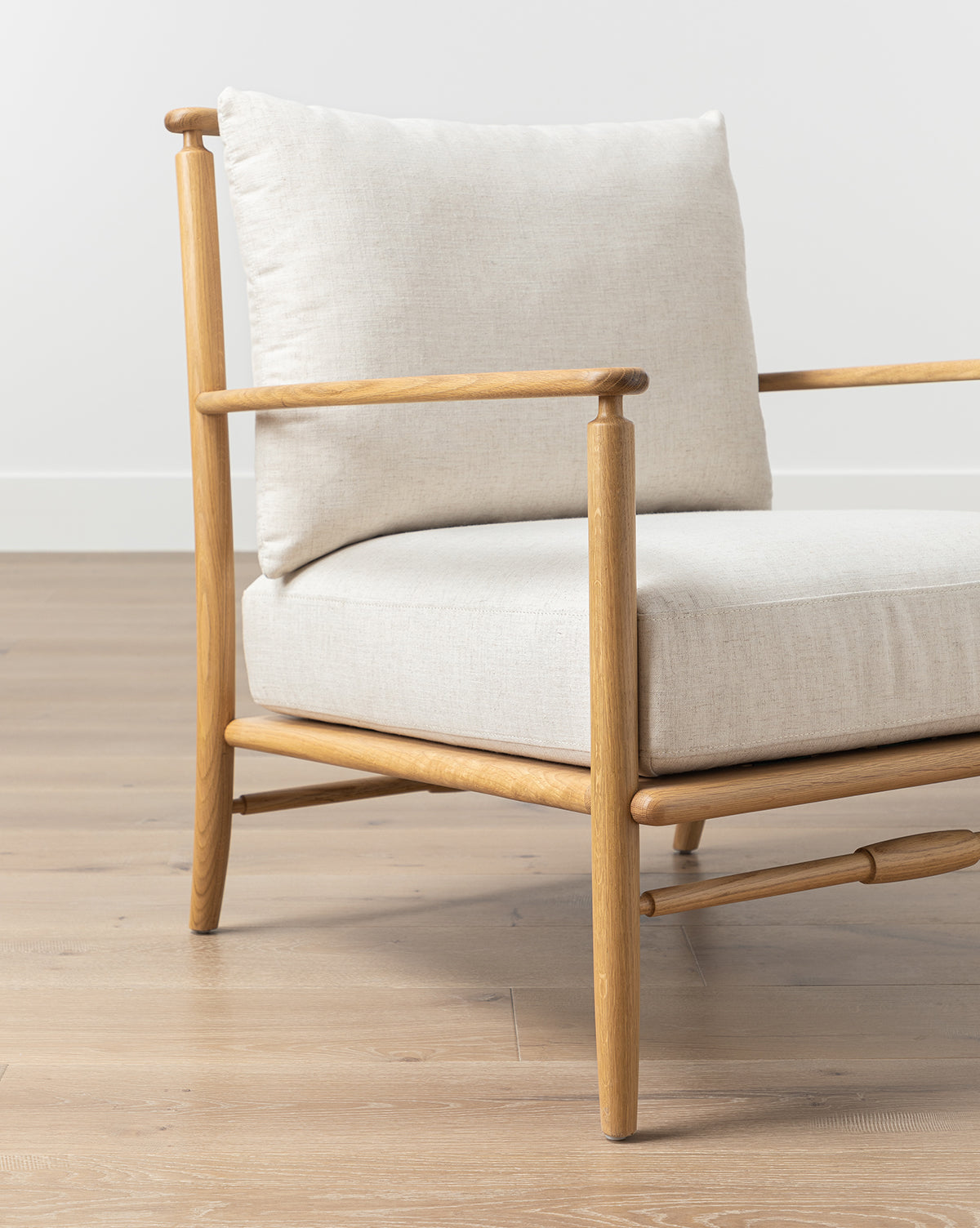 The Fenwick Lounge Chair is a minimalist modern armchair made of solid oak, featuring light beige linen cushions and clean lines, by McGee & Co.