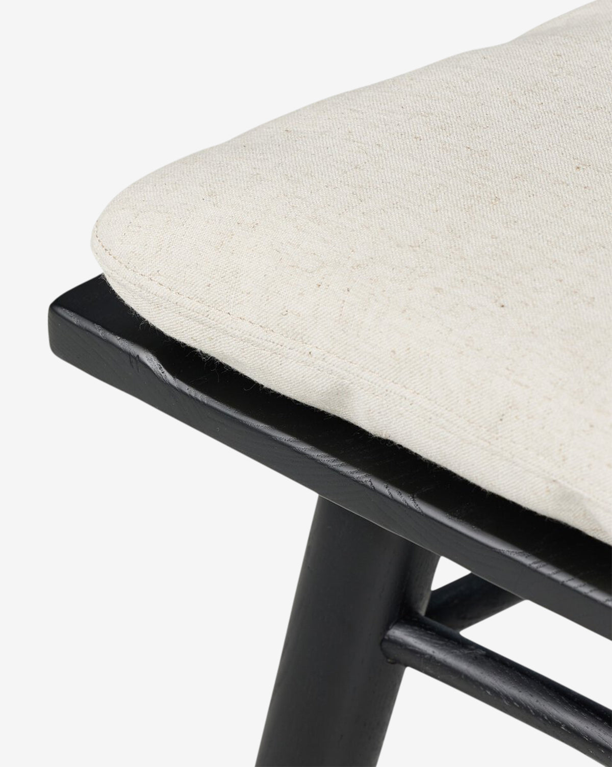 Close-up of the Fiora Dining Chairs black wooden frame and light beige cushioned seat. The removable, soft, textured cushion complements any dining table, offering both comfort and versatile style, by McGee & Co.