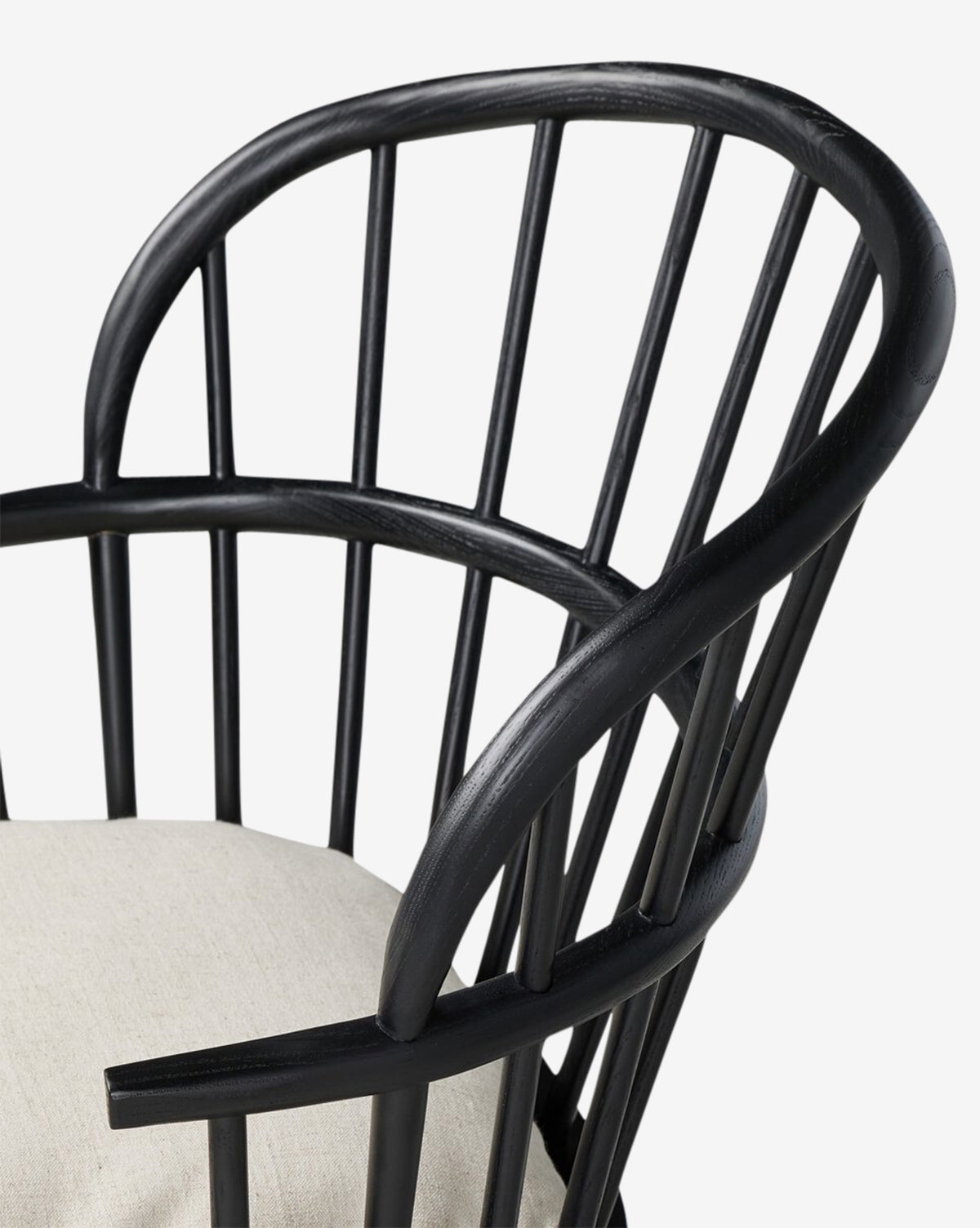 The Fiora Dining Chair is a black wooden chair with a curved spindle back, armrests, and a light beige removable seat cushion—an ideal addition to your dining table, by McGee & Co.