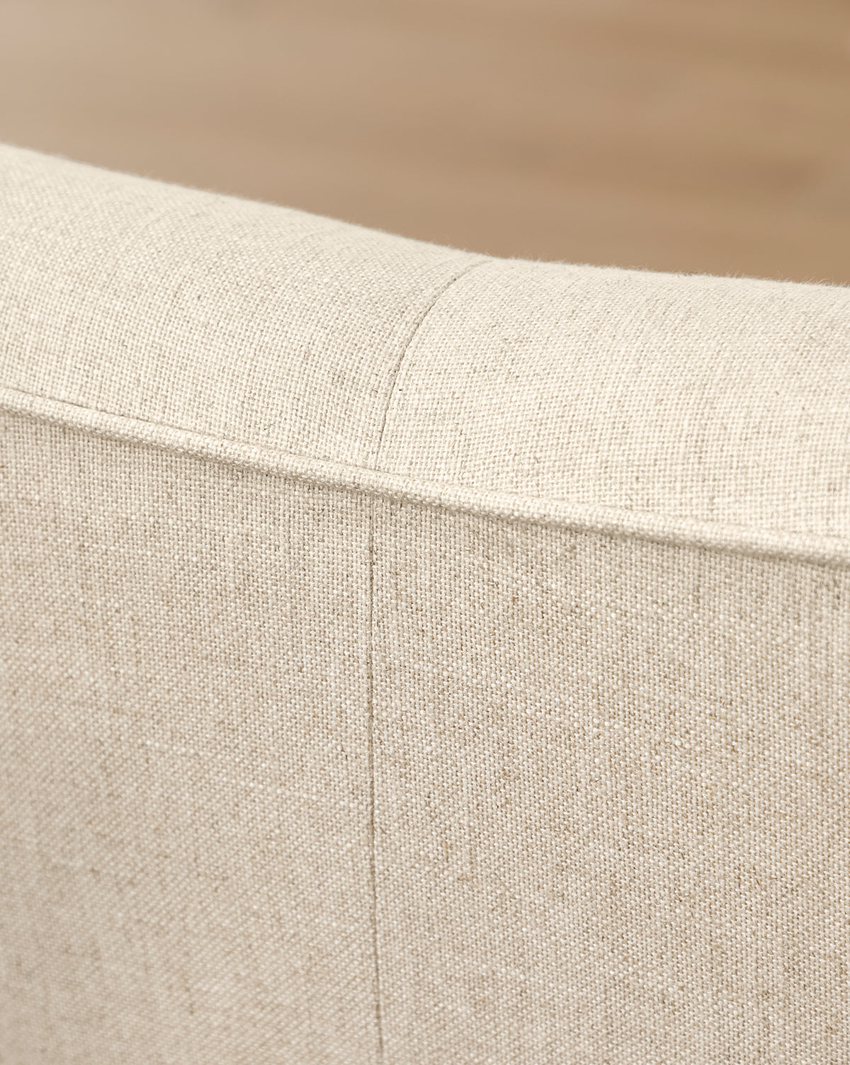 Close-up of the back and top edge of the Fletcher Sofa 76 (Ready to Ship) in beige, highlighting its textured upholstery and detailed stitching, by McGee & Co. The background appears blurred.