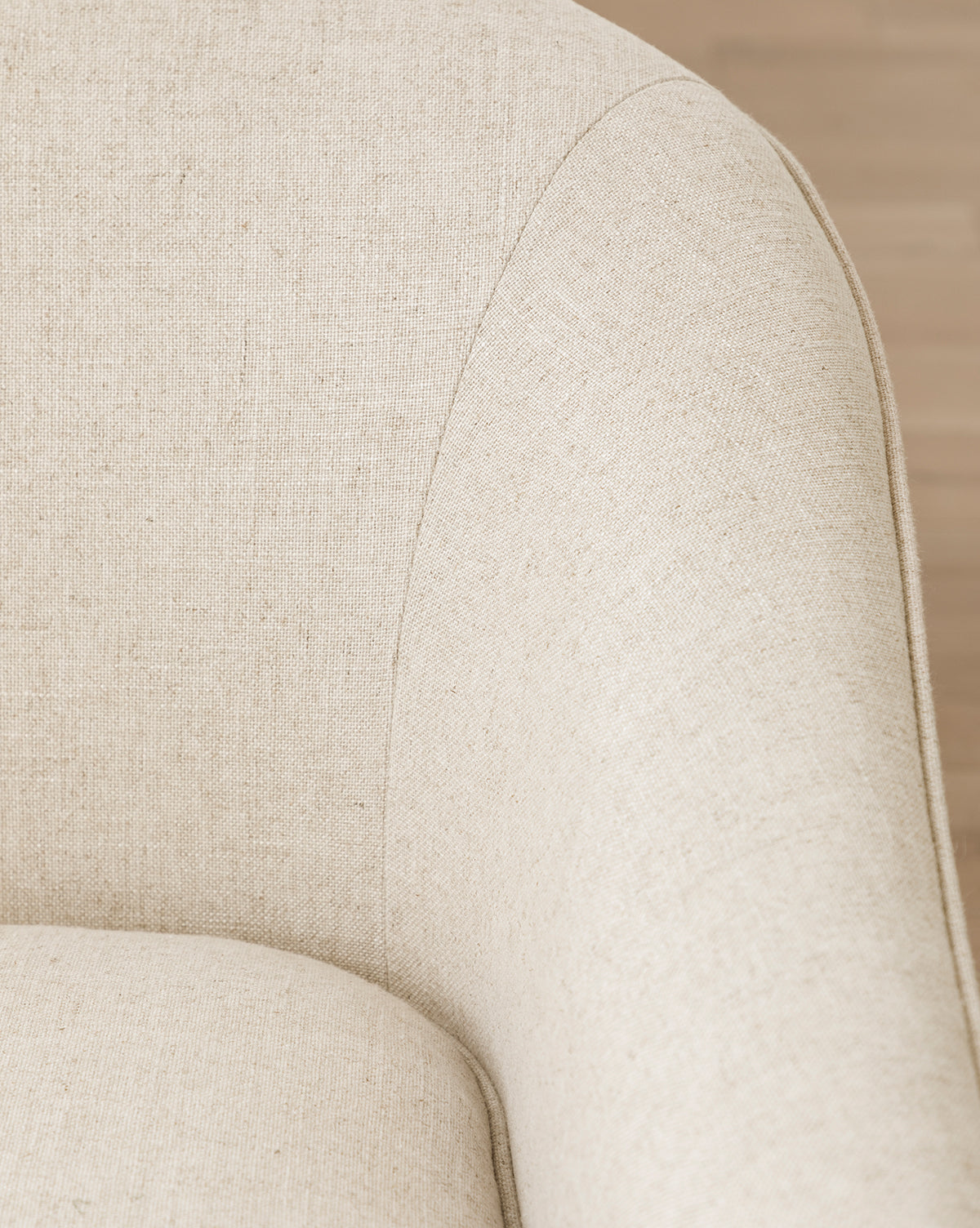 Close-up of a light beige upholstered armchair with curved armrest and textured fabric. Softly blurred background highlights the smooth lines—perfectly matching our Fletcher Sofa 76 (Ready to Ship) with customizable fabrics, by McGee & Co.