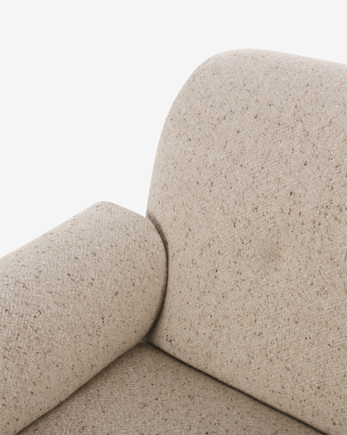 Close-up of a beige upholstered sofa with textured fabric, highlighting the armrest, backrest, and cylindrical cushion. Its neutral tone complements the Florent Chair in taupe fabric. Shown against a plain white background by McGee & Co.
